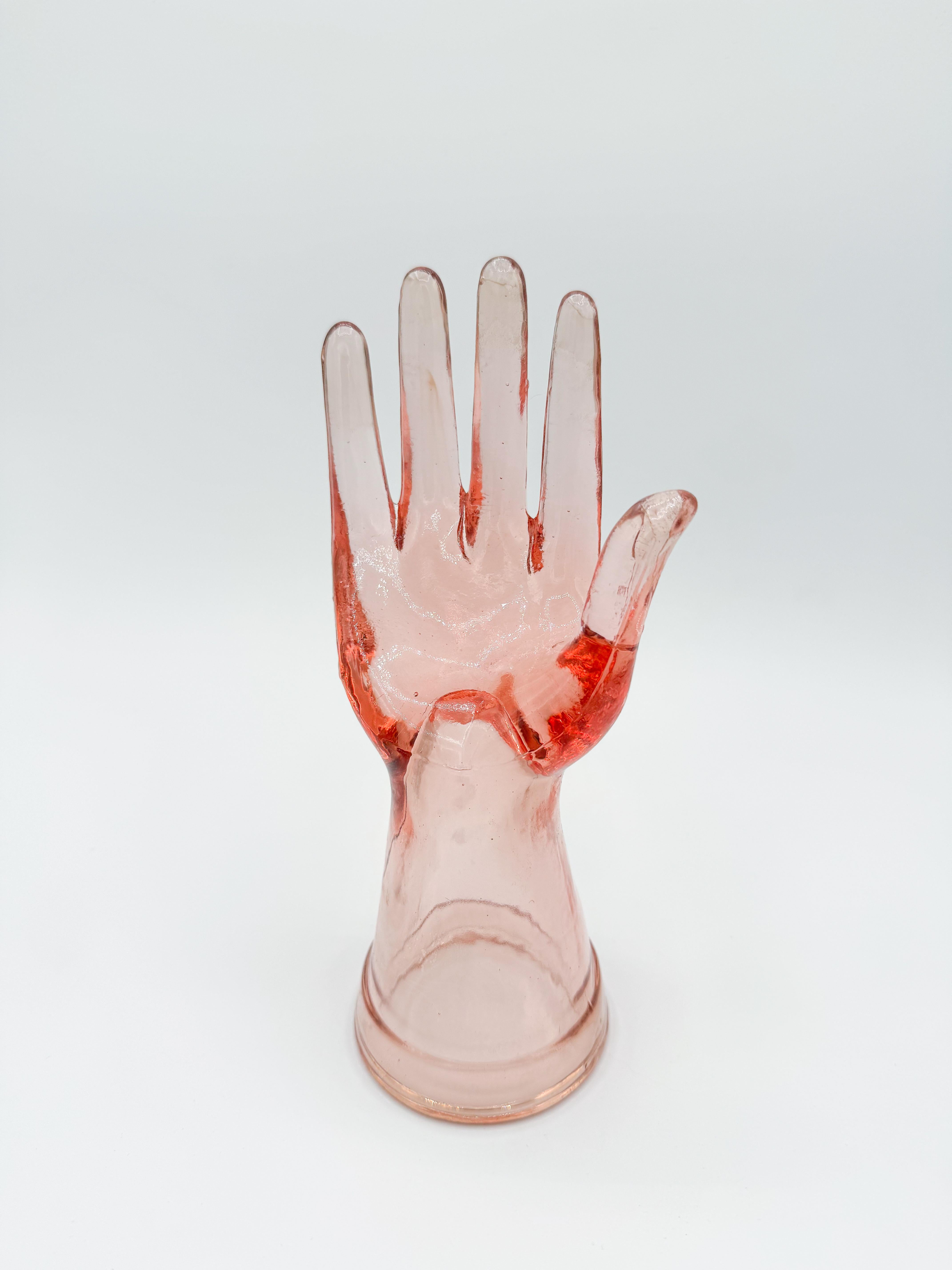 Mano di vetro rosa vintage degli anni '60. Perfetto per esporre anelli, catene, orologi, sciarpe e altri accessori di moda, questo pezzo unico aggiunge un tocco di interesse visivo a qualsiasi angolo del tuo spazio.

Realizzata in vetro rosa spesso