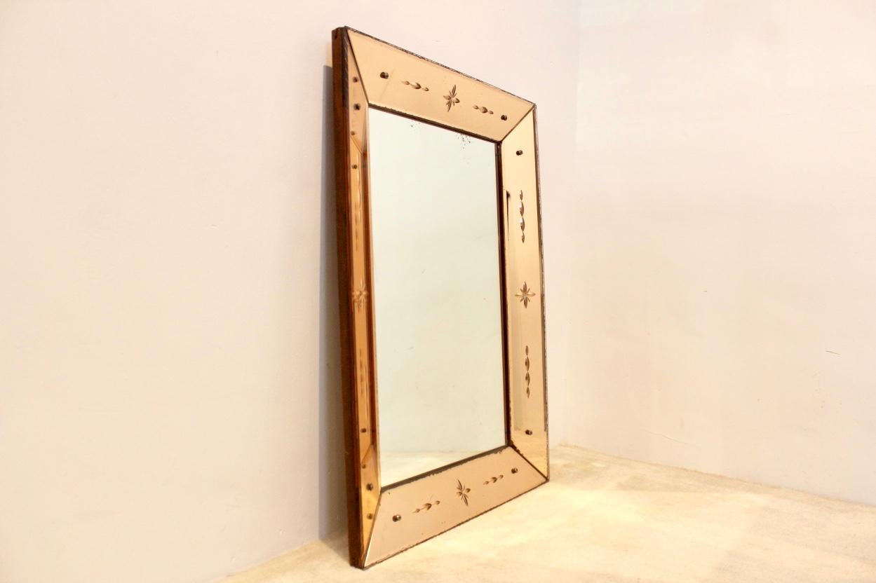 Impressive Venetian mirror with sophisticated etched patterns and constructed on a very solid Wooden back base. The mirror glass has a tremendous beautiful soft pink glow which combines perfectly with any background. Designed and made in the 1940s