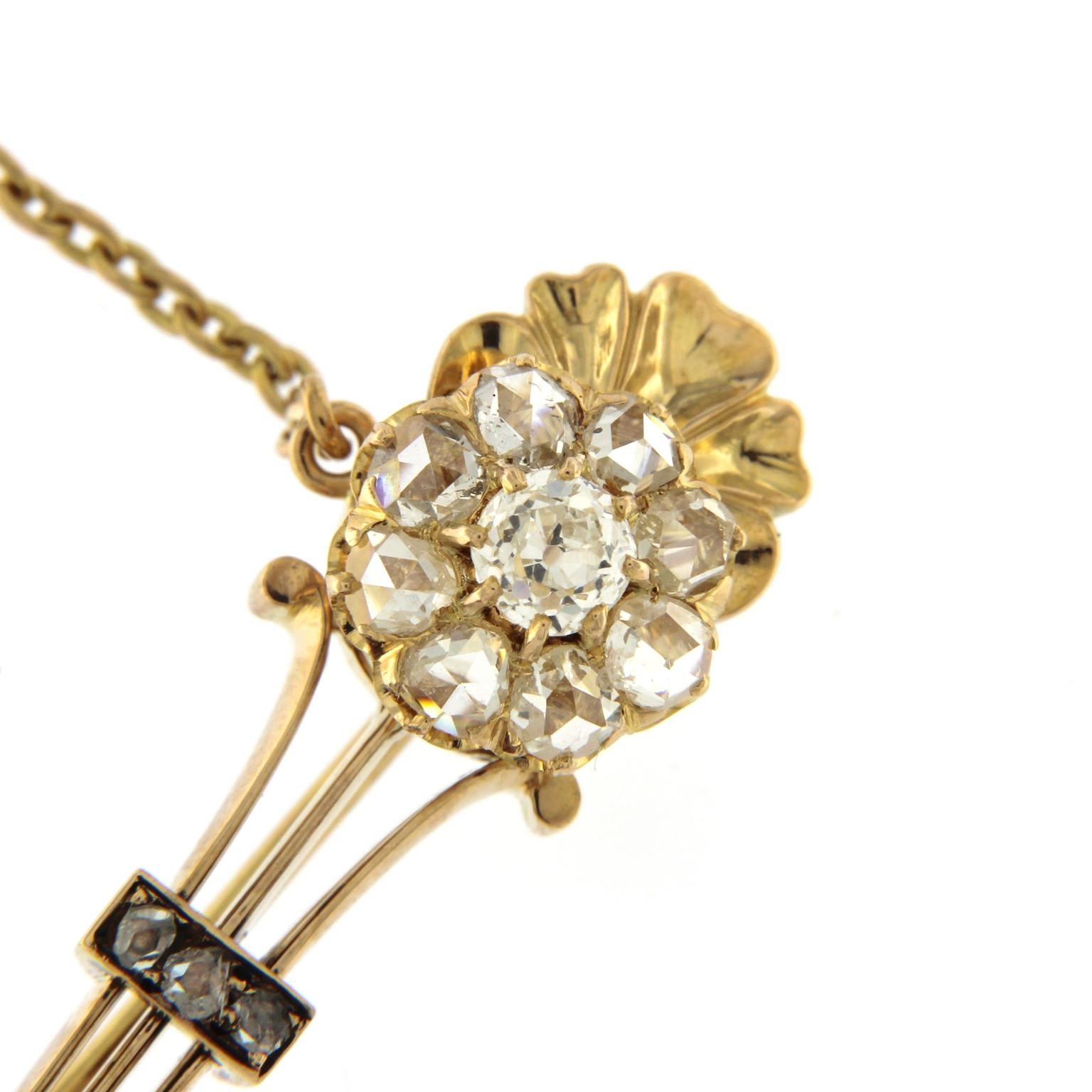Look antique pour cette broche en or rose 18k avec une fleur composée de diamants :
un brillant central de 0,45 ct et 8 diamants taille ancienne, 5 petits diamants sur la tige.
Une chaîne pour la sécurité du loquet et une petite perle sur le