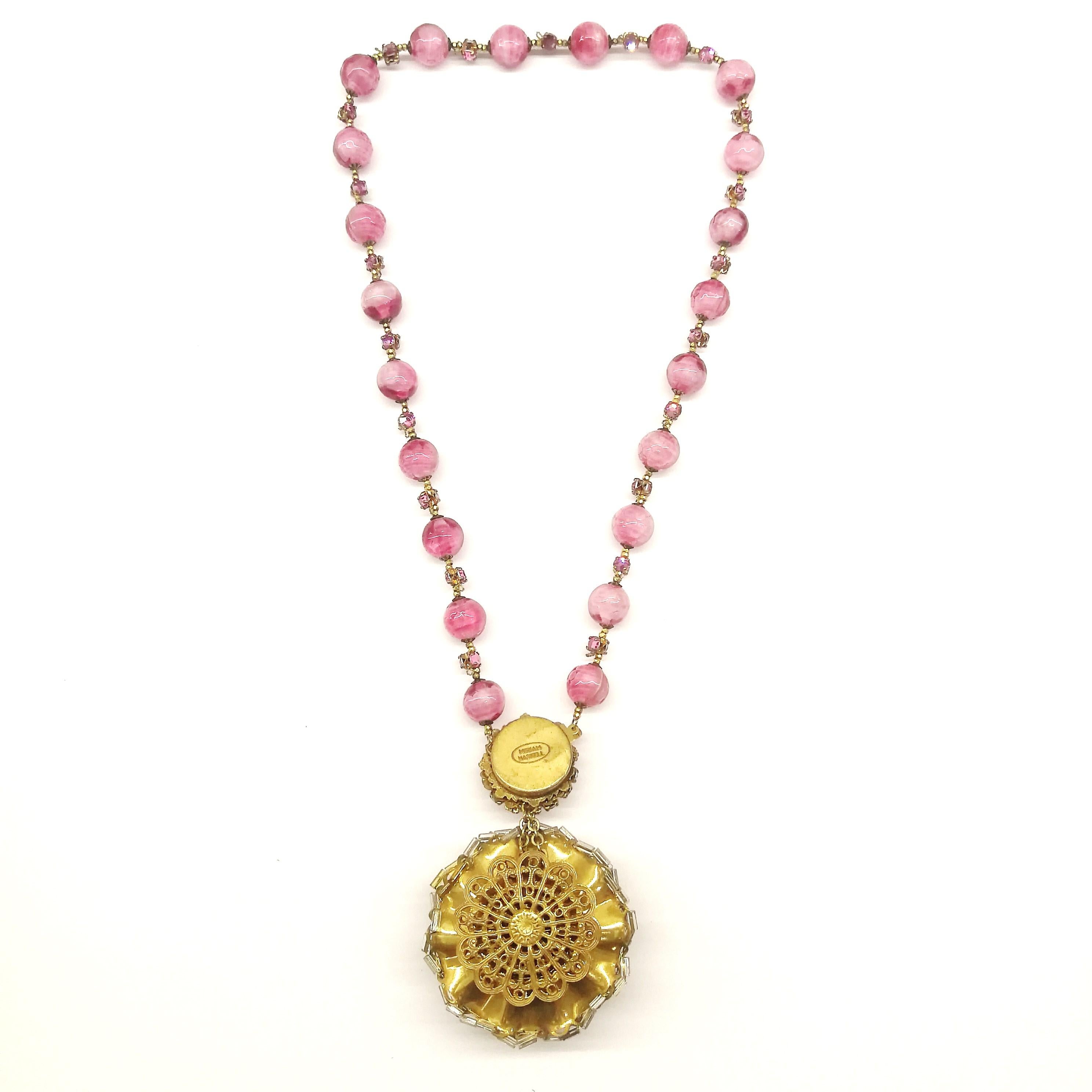 Paste 'rose montes' set between hand blown pink beads are very characteristic of Miriam Haskell jewellery, leading to a striking 'rosette' pendant, crowned in clear bugle beads, with a luscious pink bead at its centre. This lovely colour gives a