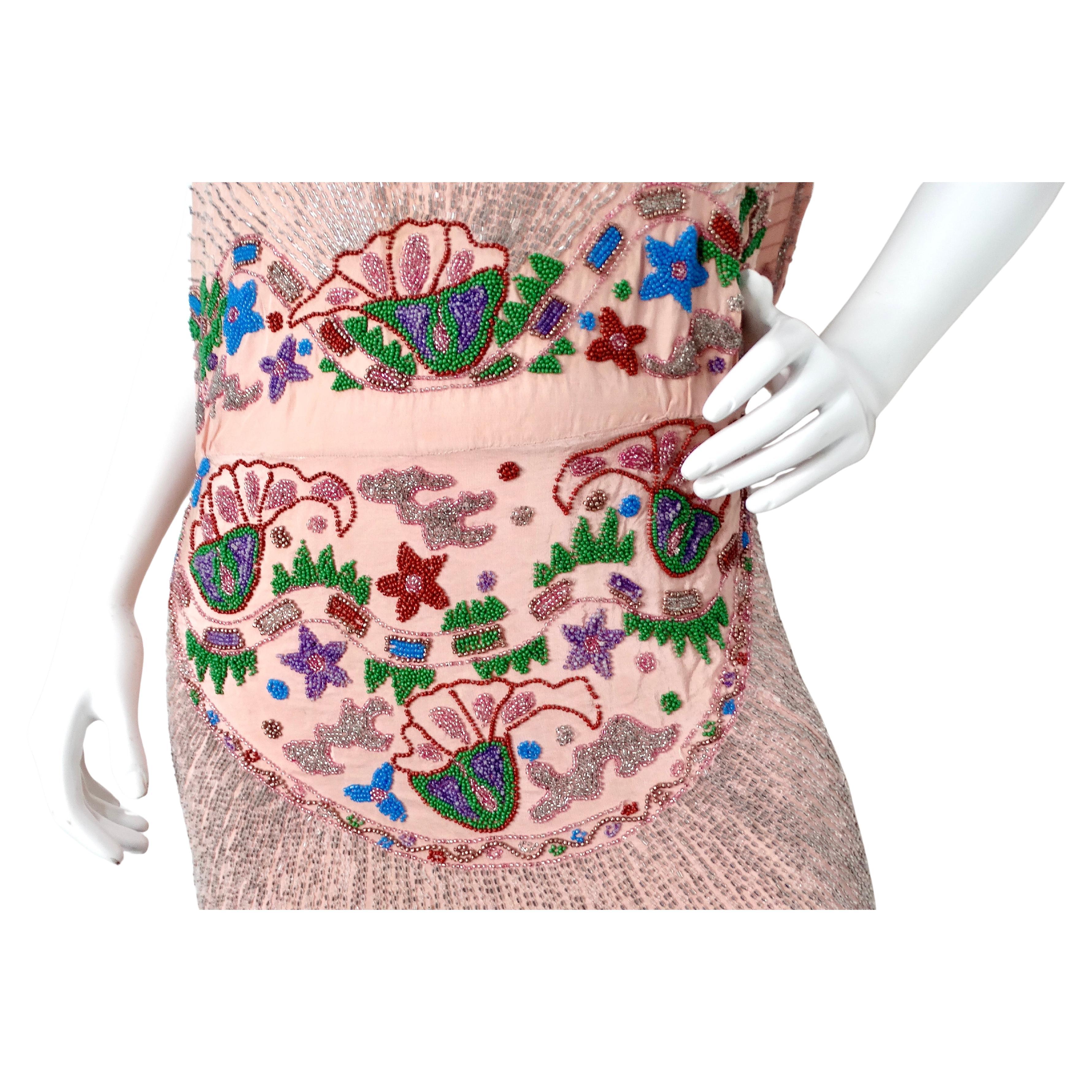 This stunning Art Deco Pink Handmade Glass Beaded Embroidery Print Sleeveless Dress is a true masterpiece of vintage elegance and craftsmanship. Meticulously adorned with countless shimmering silver beads, the entire dress radiates a captivating