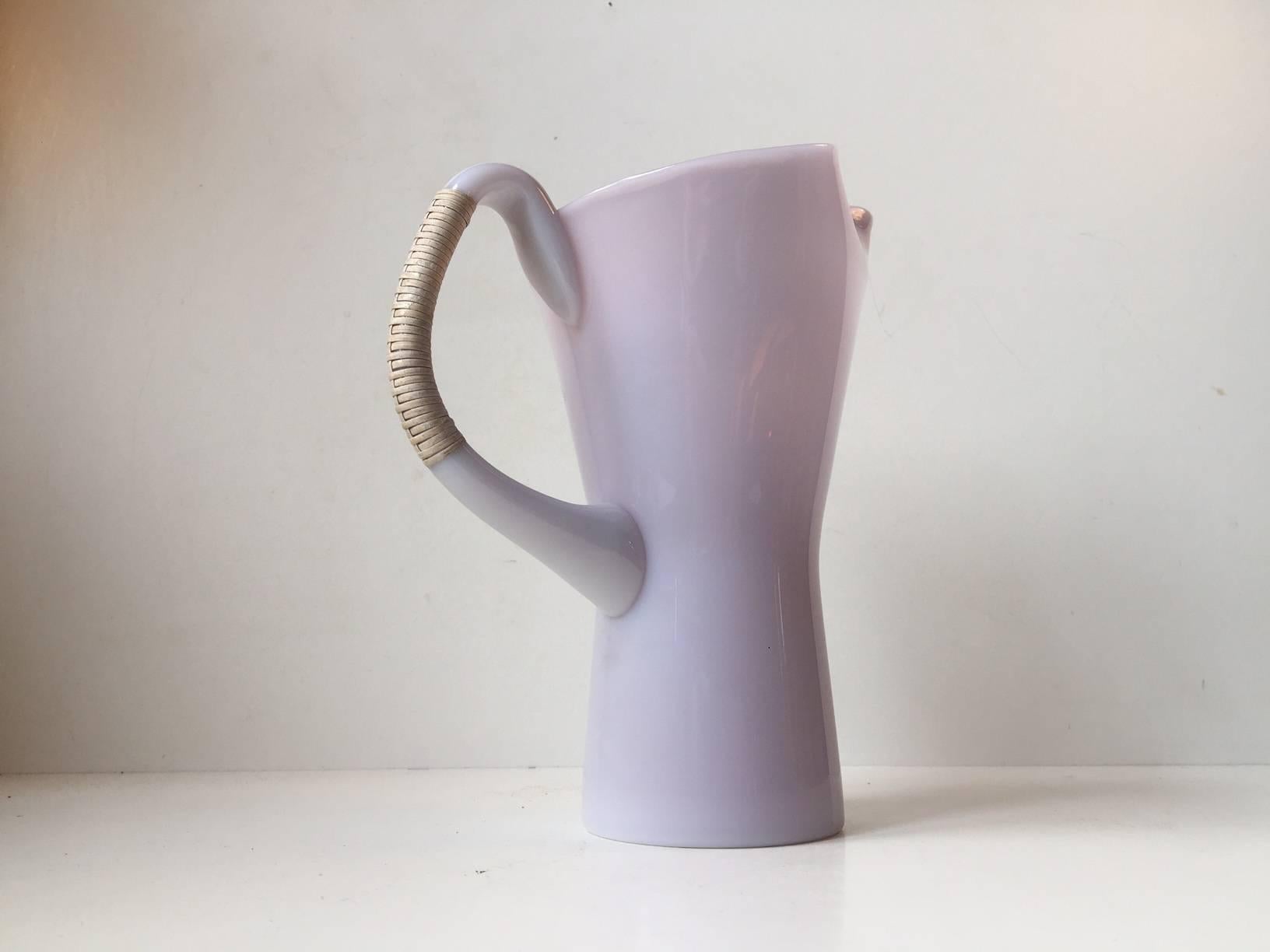 This organically shaped pitcher with a bamboo threaded handle is part of the Opaline Series by Jacob E. Bang. It is a rosé/pink version and is a unique color for this design. It is labeled with the number 7277. It was designed in the 1960s and was