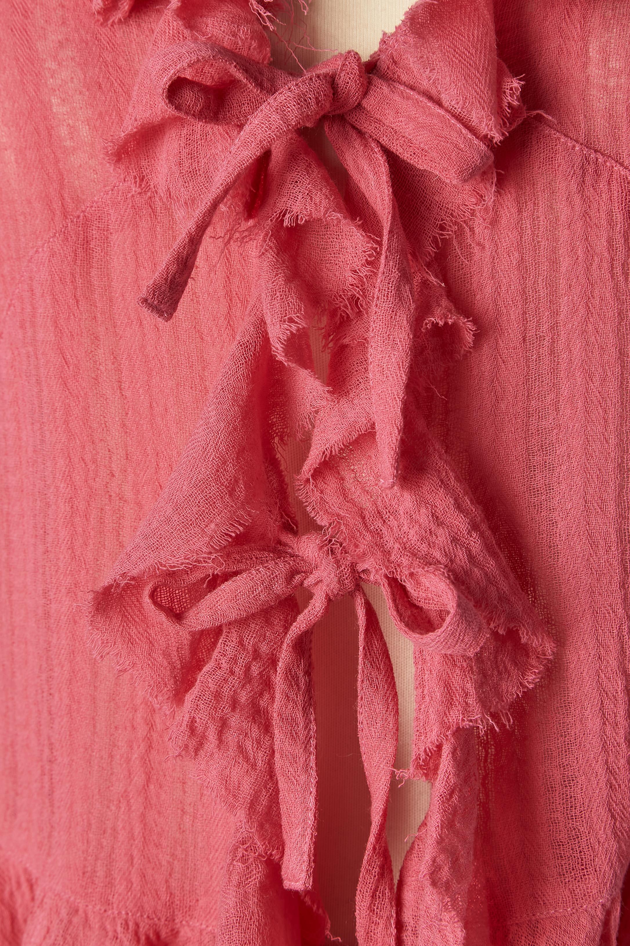 Pink jacket and skirt in thin wool with ruffles and raw edge. The vaporous look of this fabric is given by a very opened weaving. 
Lining ( only inside the skirt) : rayon and acetate. Cut-work. Bow closure in the middle front. 
The skirt is new with