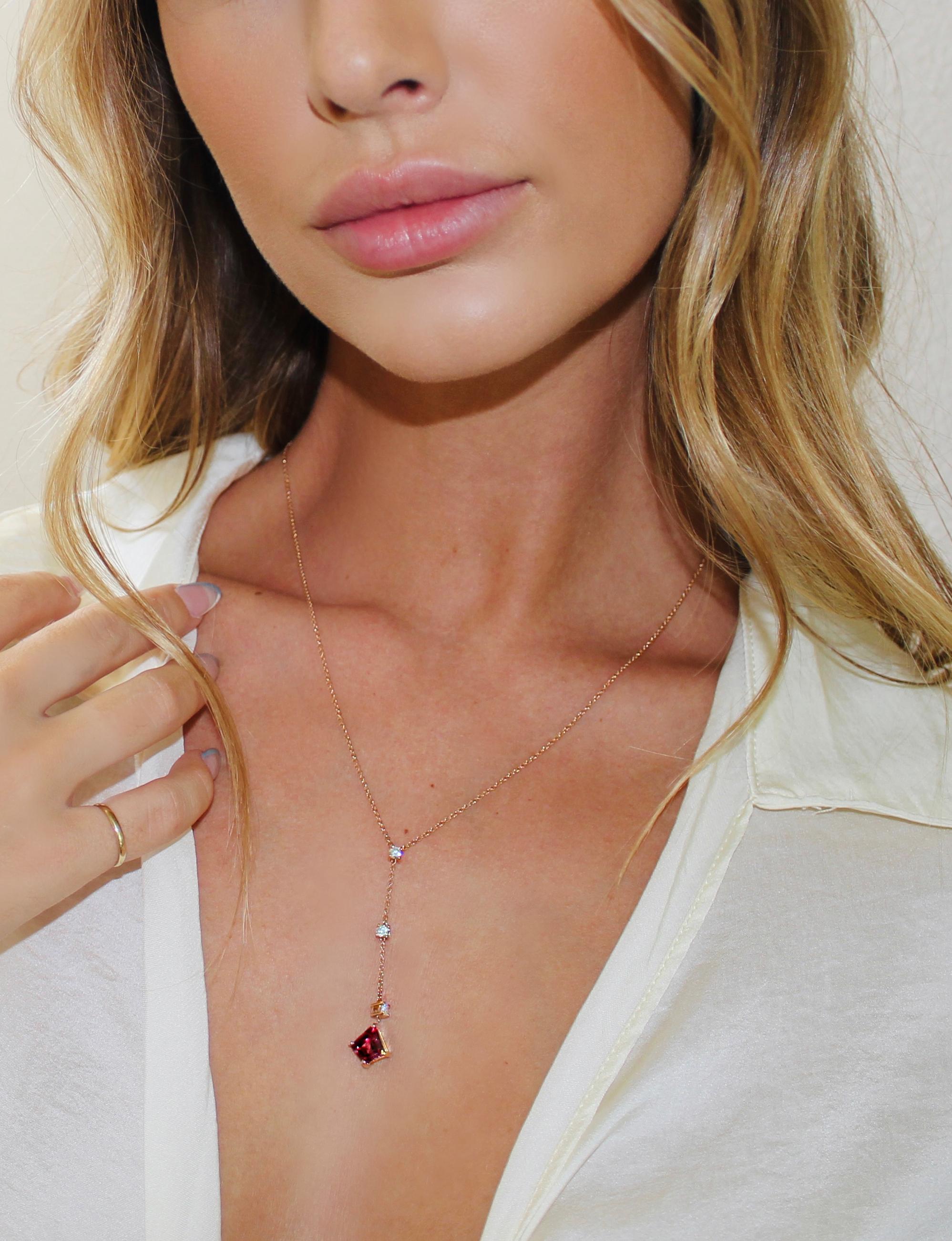 Un granato Malaya rosa a forma di aquilone è abbinato a tre diamanti rotondi in questa elegante collana a goccia. Ci piacciono le diverse tonalità di colore esibite da questo granato Malaya dal taglio unico. I granati Malaya sono in realtà un mix di