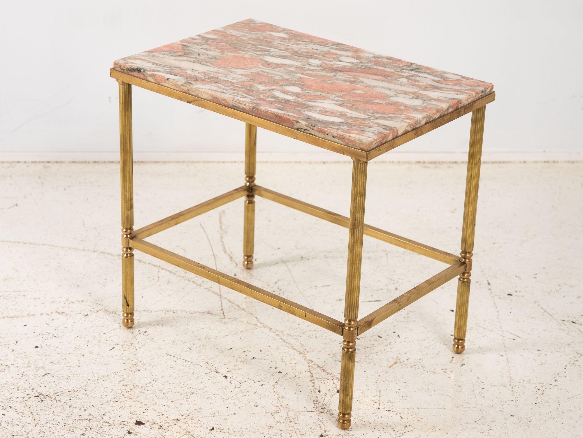 This elegant side table features a stunning pink marble top resting on a polished brass base, combining luxurious materials with refined design. Each of the four fluted legs is gracefully detailed, ending in rounded feet that enhance its classical