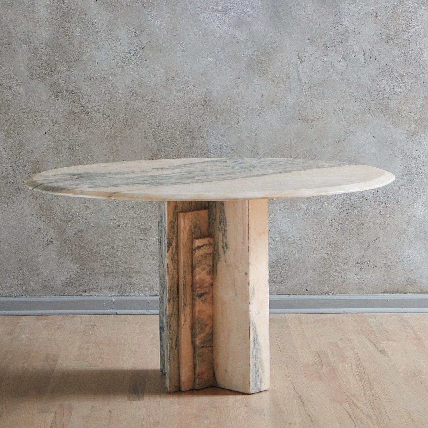 A 1970s French salmon hued marble dining table with gorgeous veining in a range of gray and taupe hues. This piece has a round tabletop with an elegant bevel edge and stands on an architectural, tiered base. Unmarked. Sourced in France, 1970s.