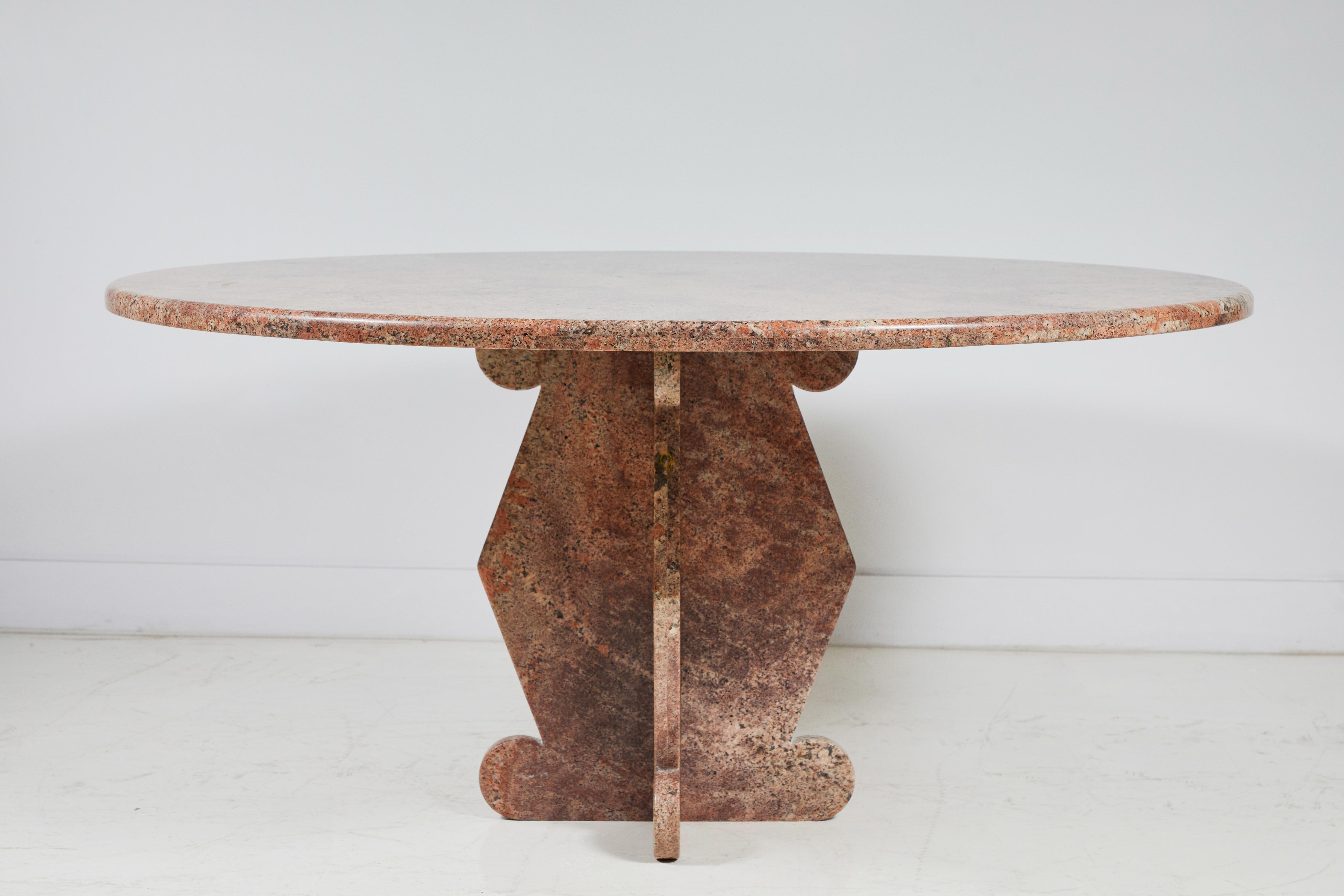 Pink marble round dining table with unique geometric base.