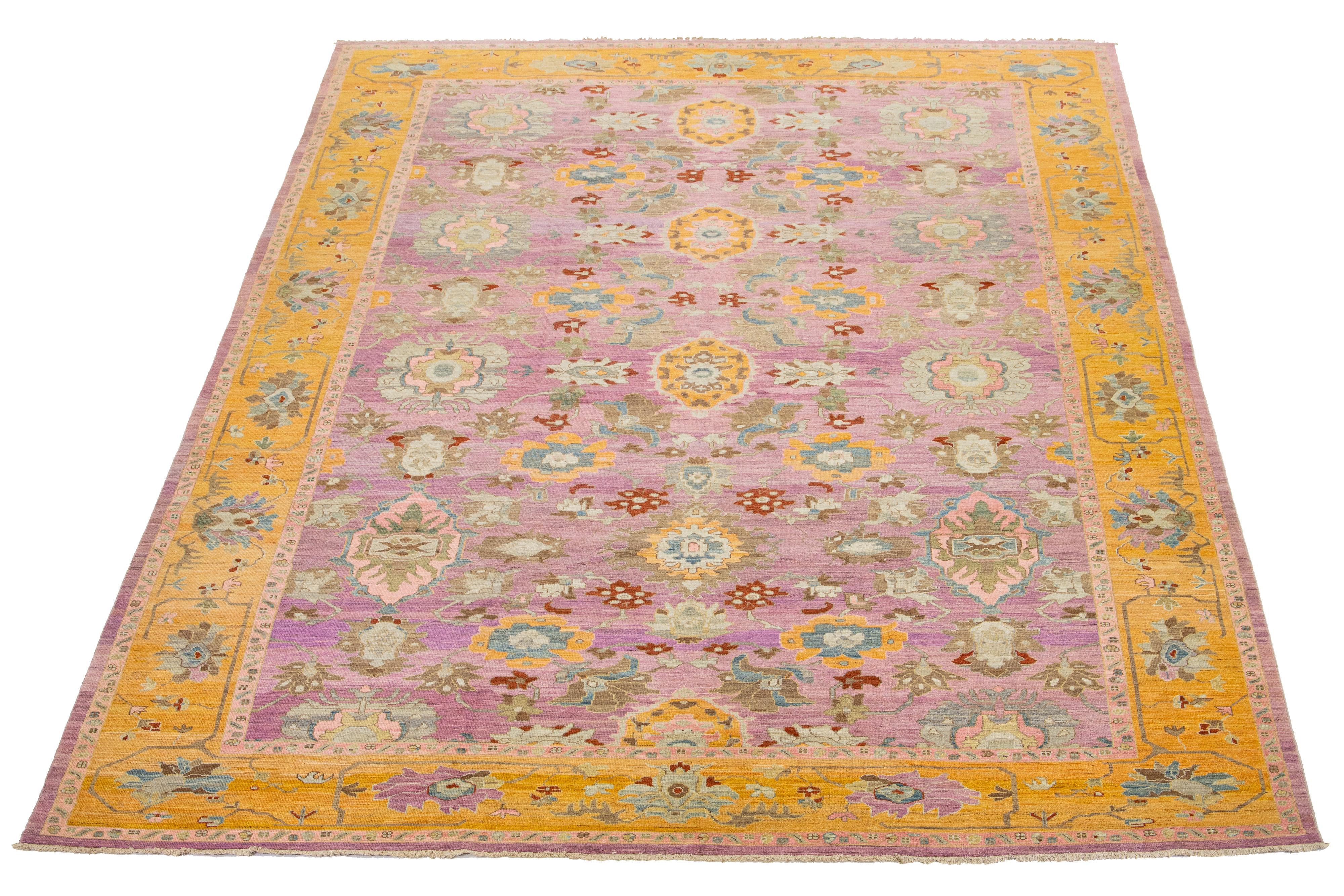 This wool rug exhibits a modern aesthetic with its Oushak-style design. It features a hand-knotted pink field and a yellow border adorned with vibrant floral patterns that extend throughout the entire rug.

This rug measures 12'1