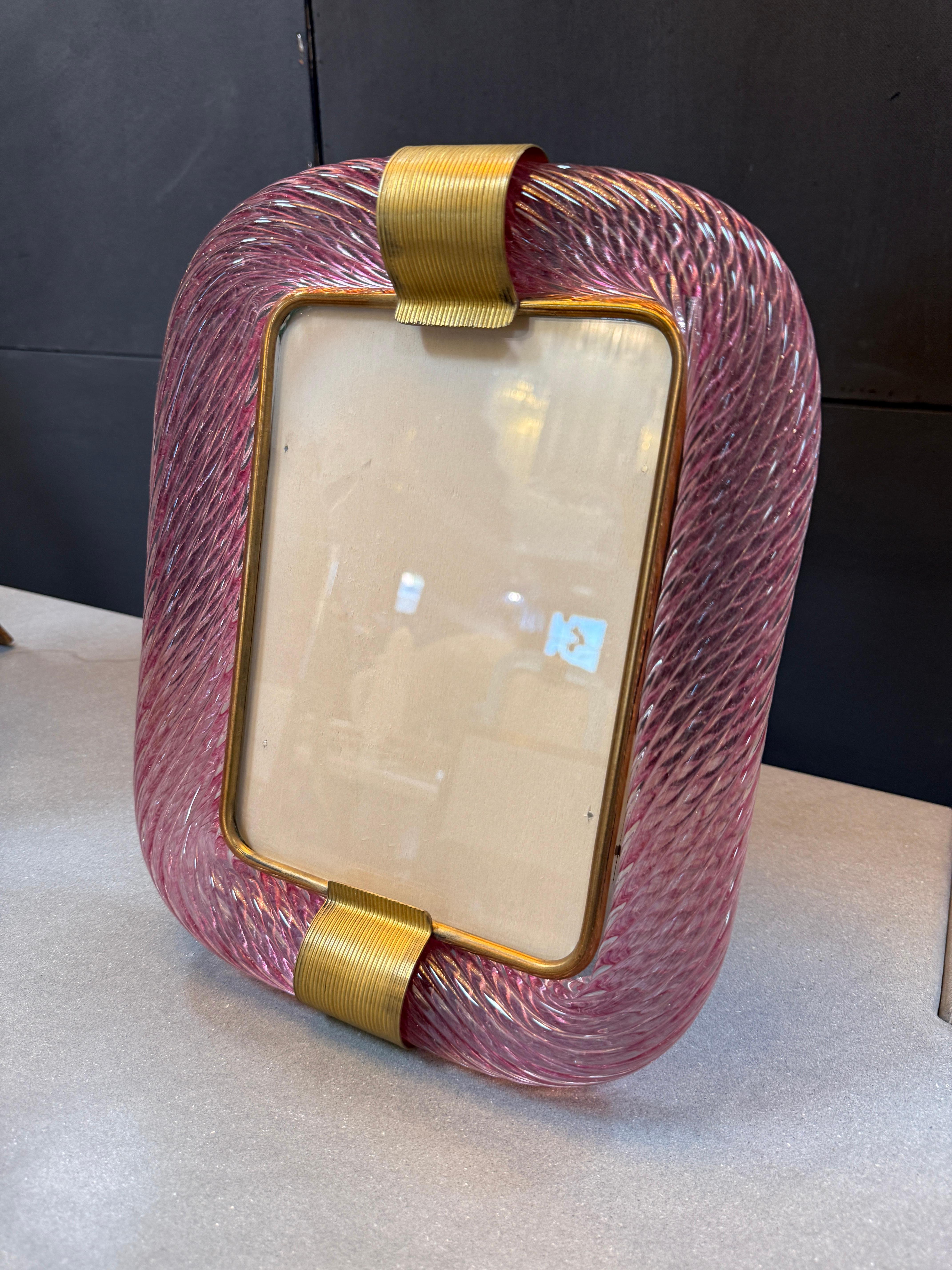 Una sofisticata cornice italiana della metà del XX secolo, realizzata a Murano con un'eccezionale arte vetraria. La cornice presenta una radiosa tonalità rosa, arricchita da una superficie contorta e strutturata che brilla di profondità e dimensione