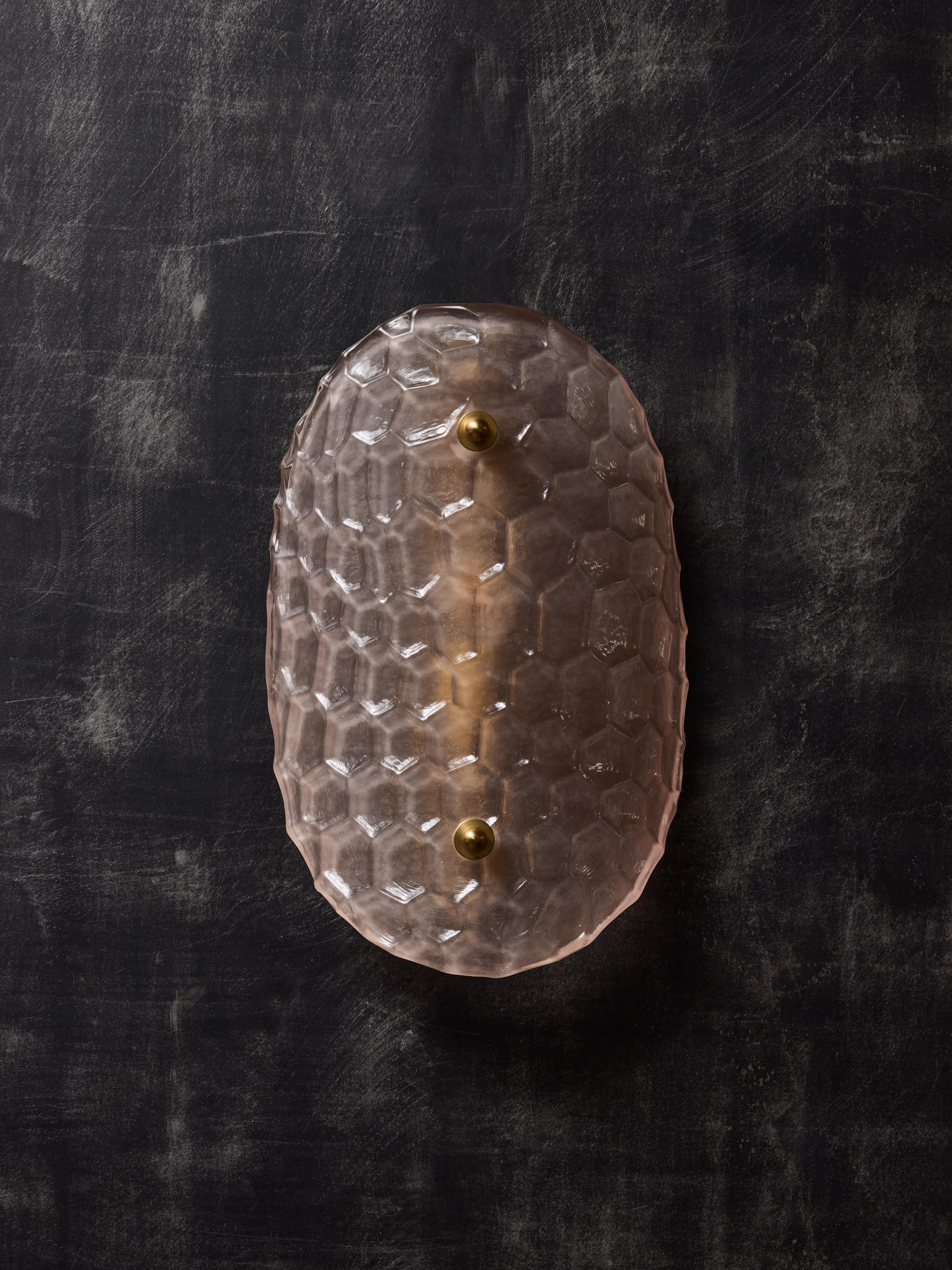 Wall sconces made of a metal back plate, curved Murano glass diffuser with an embossed honeycomb pattern tinted in pink. Finished by brass hardware.

One source of light per sconce