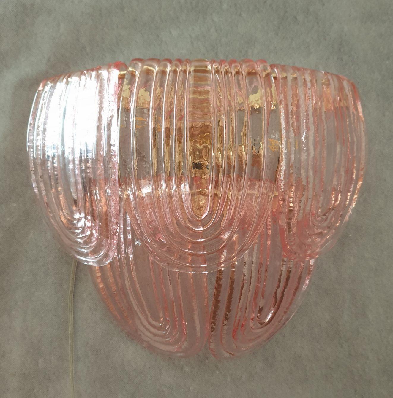 Mid-Century Modern pair of Murano glass sconces, attributed to Mazzega, Italy, 1980s.
The Italian sconces have a neoclassical style, and are very elegant.
The pair of sconces is made of translucent light pink Murano glass and a gold plated