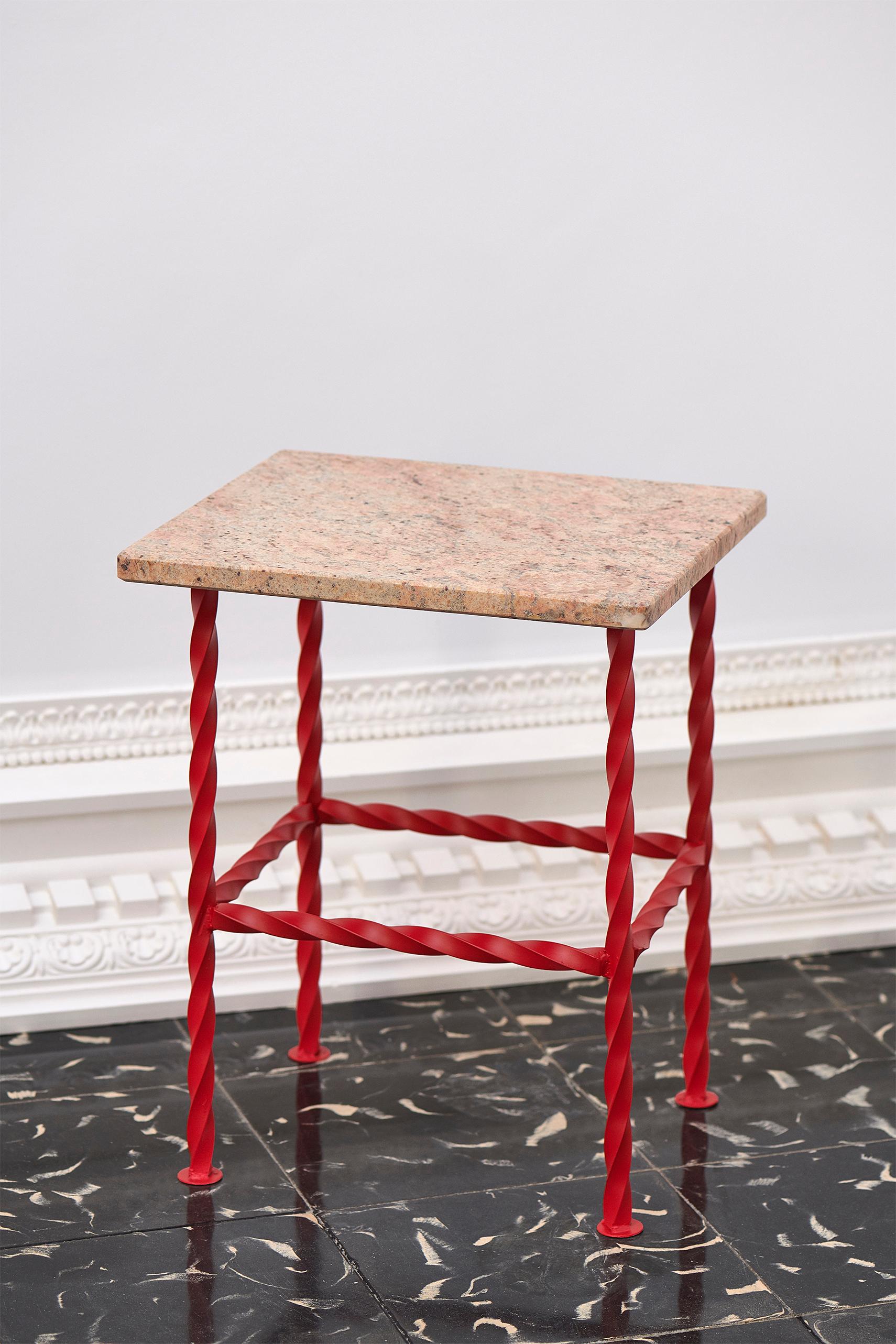 Salomón is a side table made of a light cream natural granite top with a smooth shiny hand-finish surface. It has a red curved wrought iron leg structure.

It is a small side table which fits in any part of the house, giving a strong presence