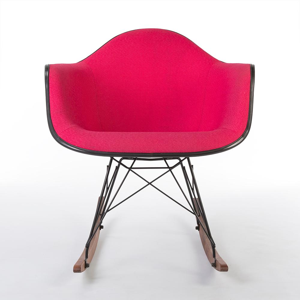 This is an original, used Herman Miller Eames upholstered armchair, with vibrant, sophisticated pink fabric, enclosed on top of the black fiberglass shell. The RAR base is new, made out of beautiful, natural walnut wood, with black detailing of a