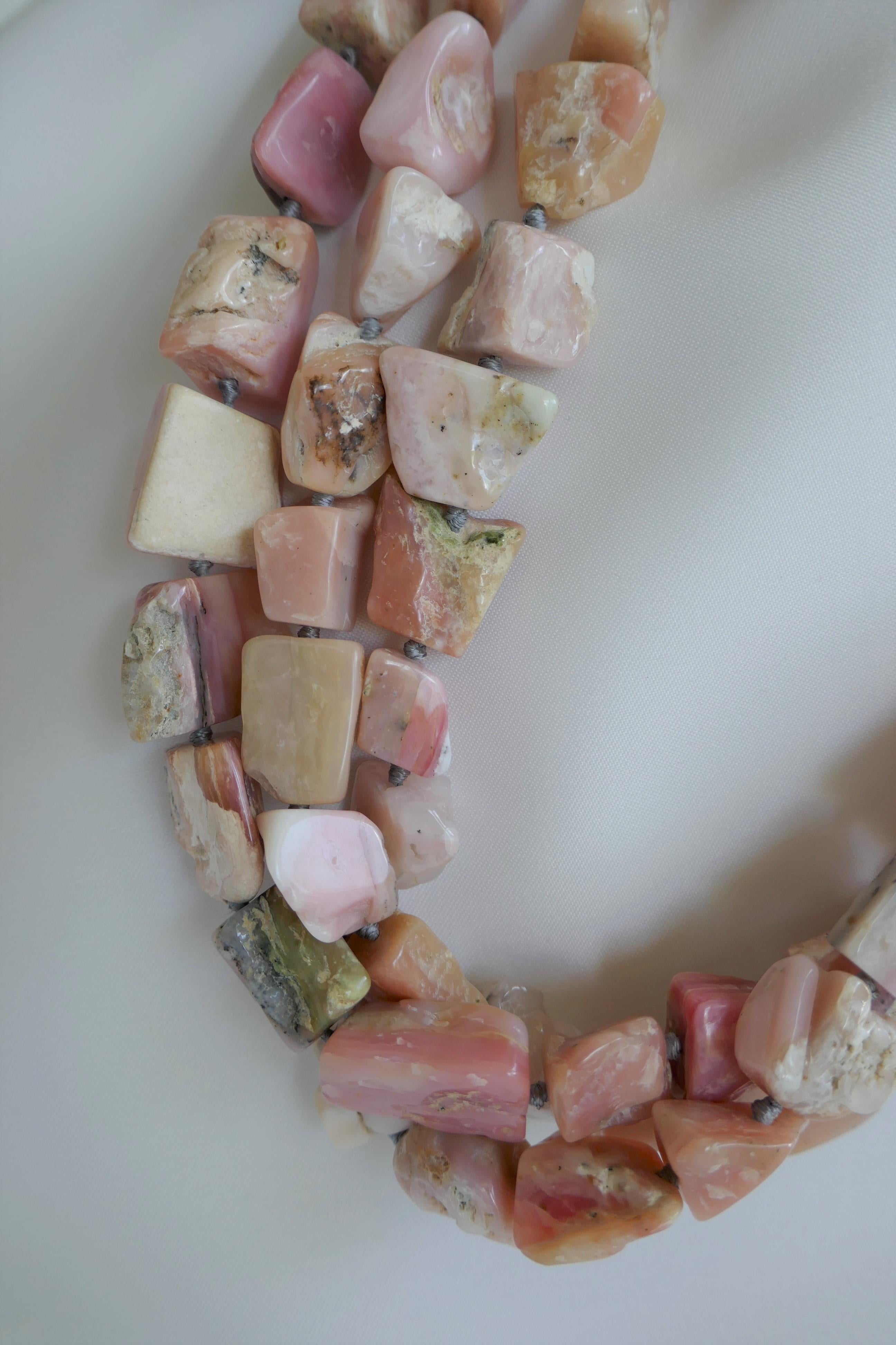 This necklace in one of a kind. It is definitely  a statement necklace that looks beautiful on.  The pink opal nuggets have a lot of different tonalities. The necklace is three strands and is individually knotted on grey silk thread. The nuggets are