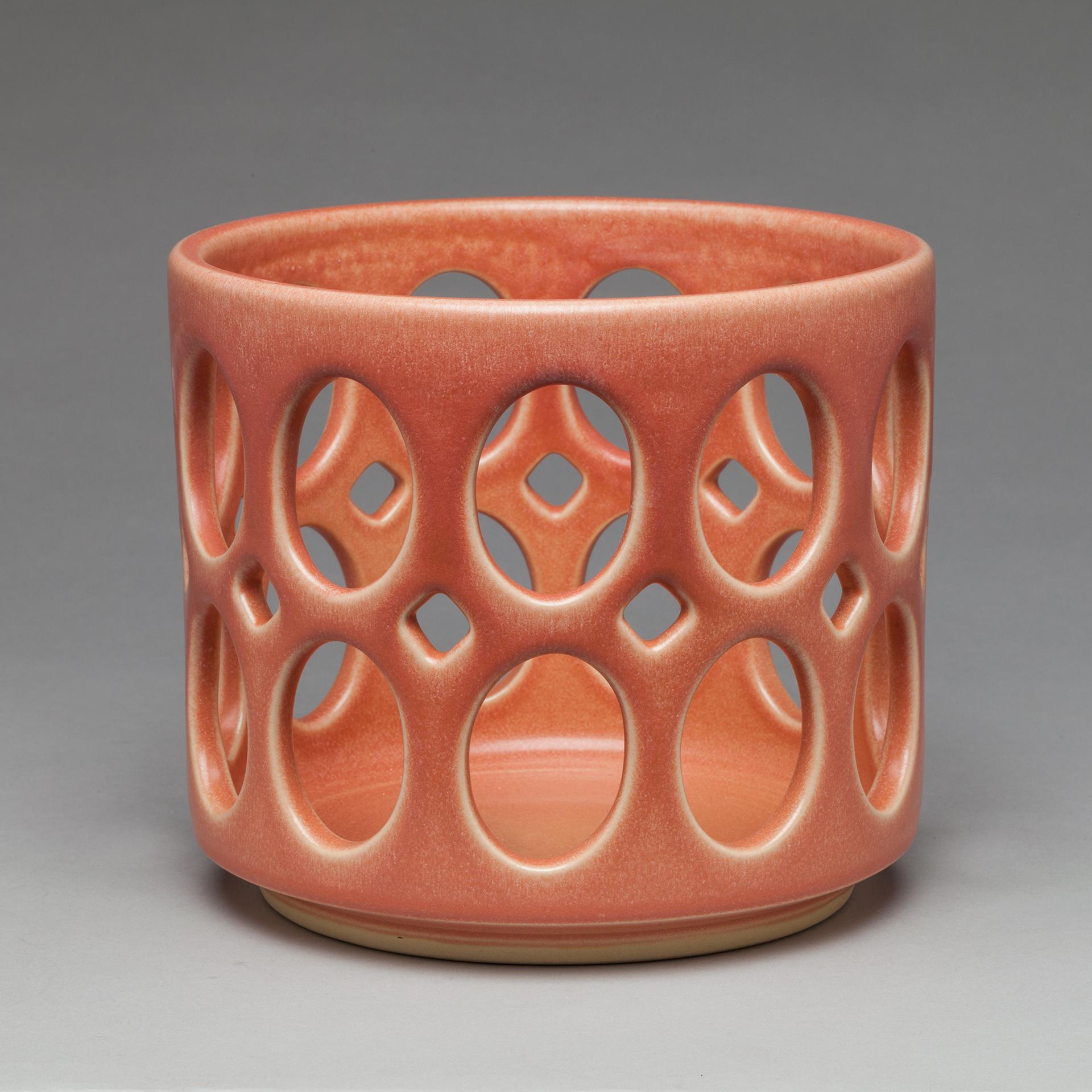 Inspired by Mid-Century Modern design, this bowl is wheel thrown and hand pierced stoneware with a deep pink satin glaze. Small holes are created when the clay is still wet and then each hole is painstakingly enlarged and smoothed when the clay is