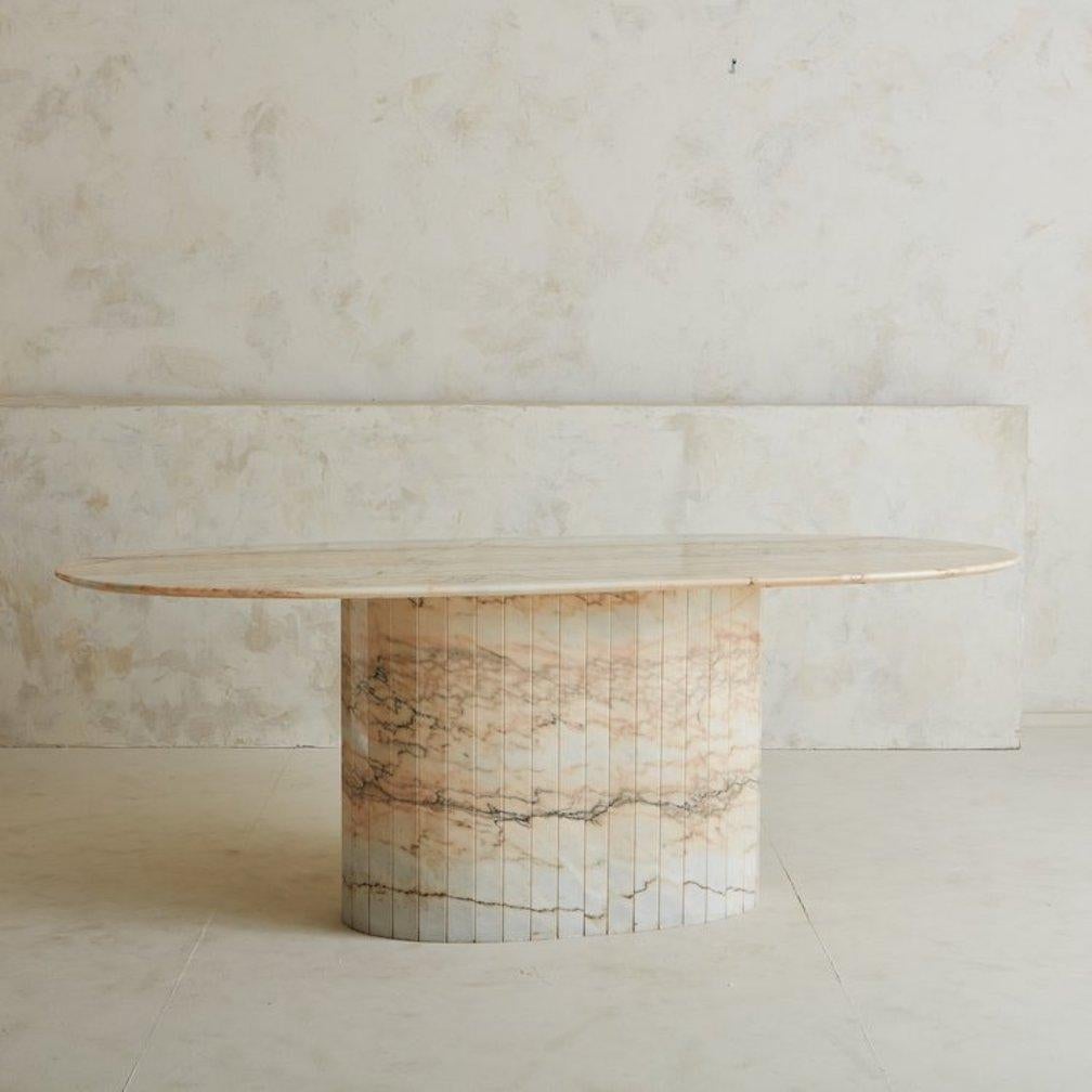 An oval marble dining table sourced in Europe with beautiful pink and grey marble veining. This table has a polished finish and features a bullnose edge top and an oval tessellated stone pedestal base. Spain, 1970s.

Dimensions: 60.5