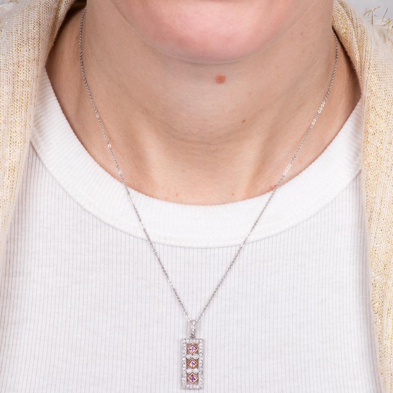 This pendant necklace features approximately 0.40 carat total weight in natural round diamonds and 0.20 carat total weight in natural pink princess cut sapphires. It is set in a 14 karat white gold rectangular pendant with a diamond bail. The chain