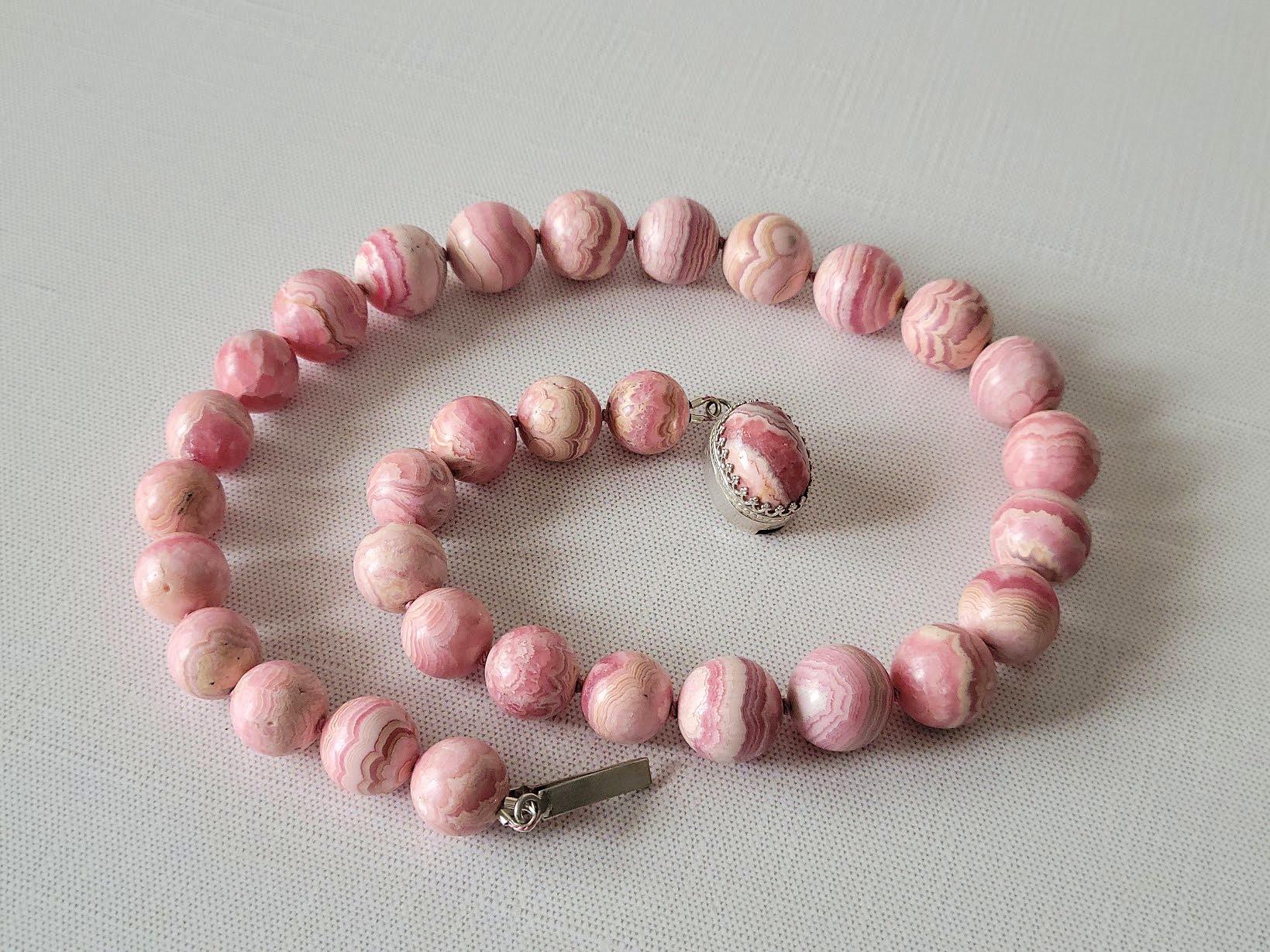 The necklace measures 19.5 inches (50 cm) in length. The smooth, round beads range in size from 13.5 mm to 15.5 mm.

Crafted from natural rose-red rhodochrosite, this piece boasts an authentic, untreated color of superior, high-grade quality. The