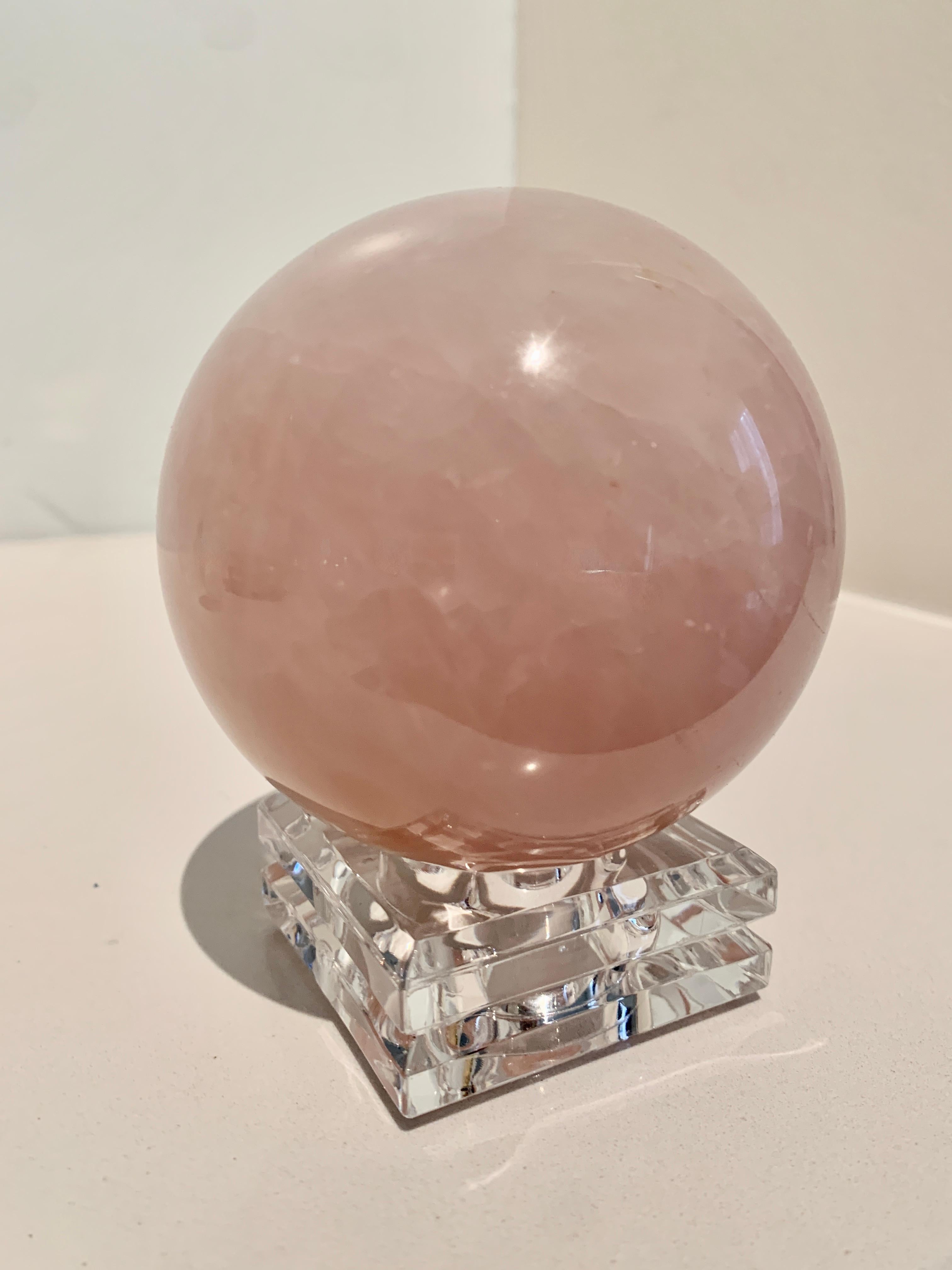 A wonderfully Blush pink crystal ball, on a stand an acrylic cut stand. The stand looks to be crystal and both have a brilliant aura and energy... a compliment to any desk as an Object of art of paper weight. A great gift.