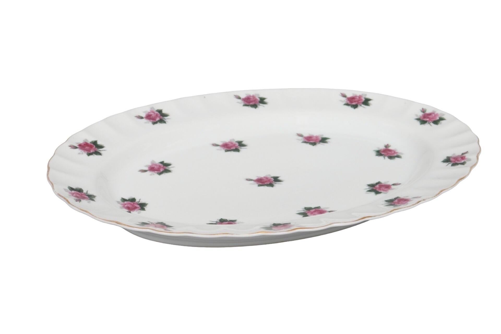 An oval ceramic serving platter made by Bond Ware. Decorated with a repeating pink rose motif and a ruffled lip, edged in gold. Marked Bond Ware Hand Painted underneath.