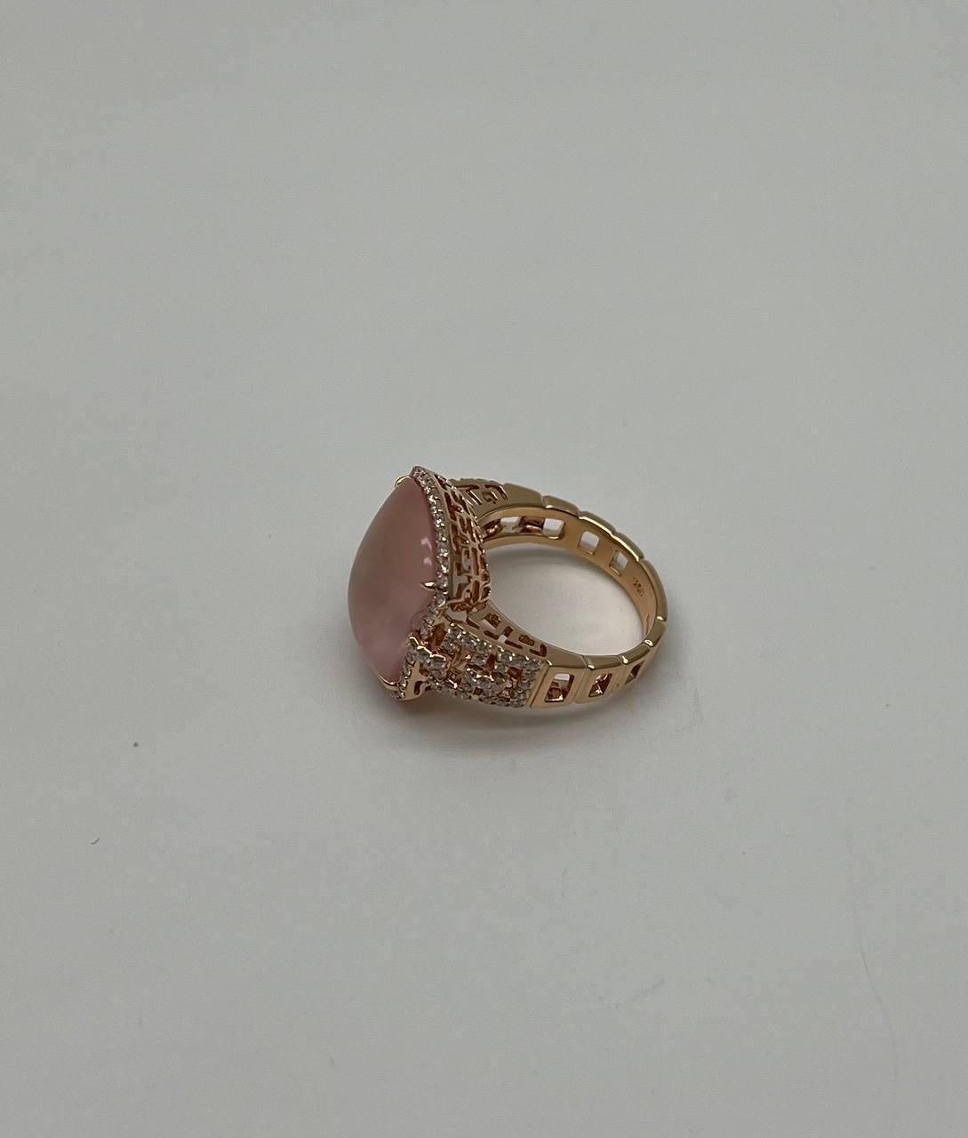 A stunning ring.  This exquisite piece features a captivating rectangular pink rose quartzset in a luxurious gold band. The stone is surrounded by a halo of sparkling diamonds, enhancing its soft hue and adding a touch of elegance. The intricate