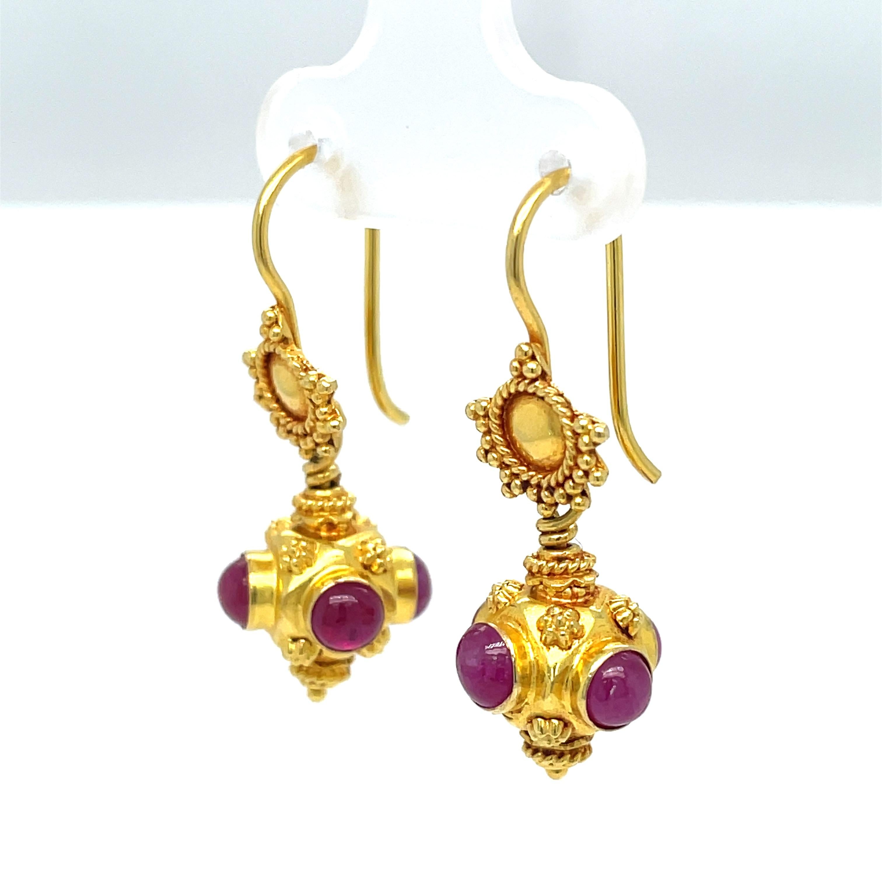 Brillante y colorido, este par de pendientes de tamaño modesto exhibe cuatro alegres cabujones de rubí rosa de 3,5 mm en cada uno, engastados en bisel en un elegante engaste ornamental de oro amarillo de 18 quilates. Anclando la gota hay un disco