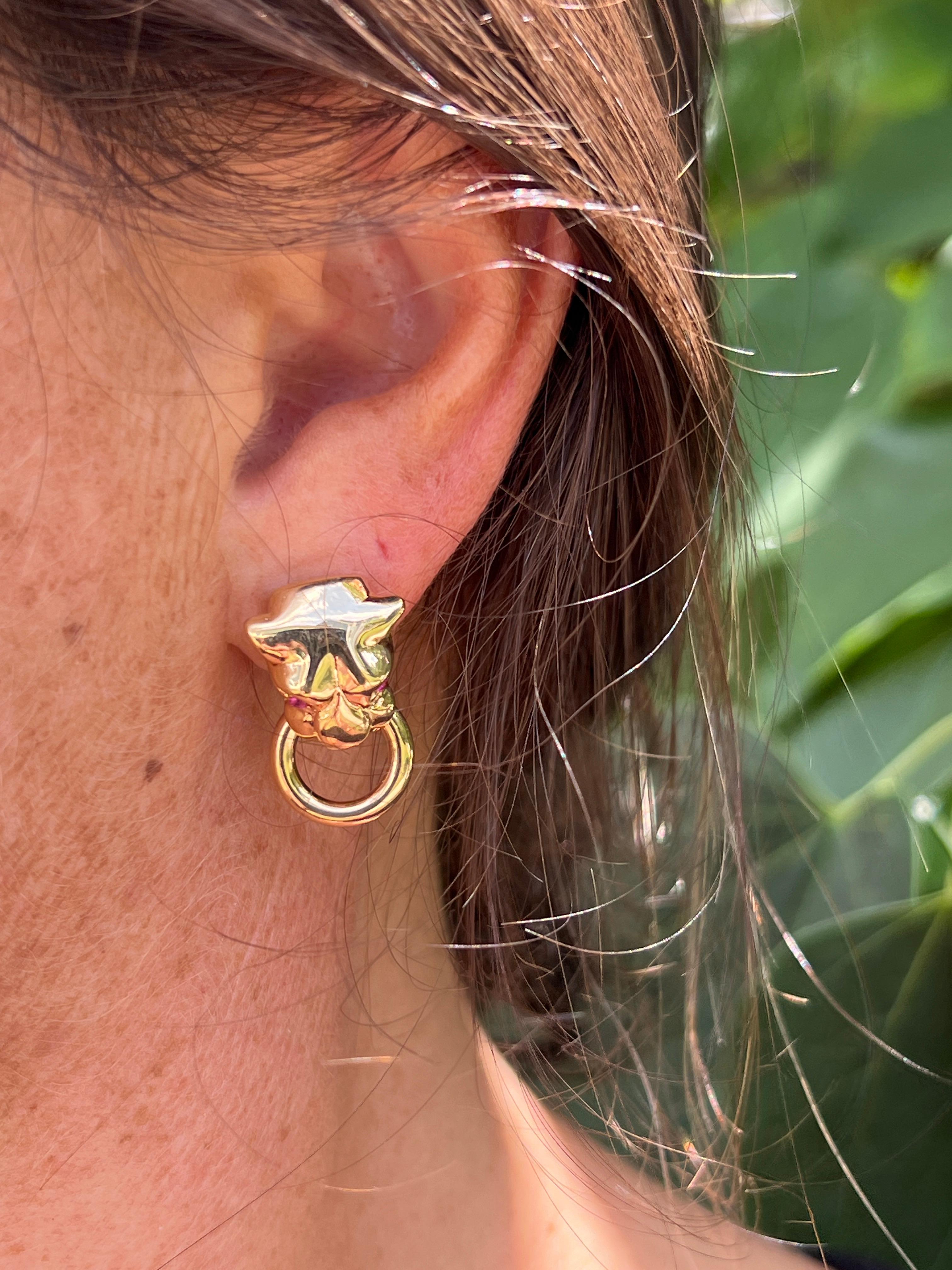 Embrace bold style with this pair of 1980s 18-karat yellow gold panther door knocker earrings. These hollow, moveable earrings are adorned with three round synthetic pink sapphires and one round pink sapphire of unknown origin, totaling