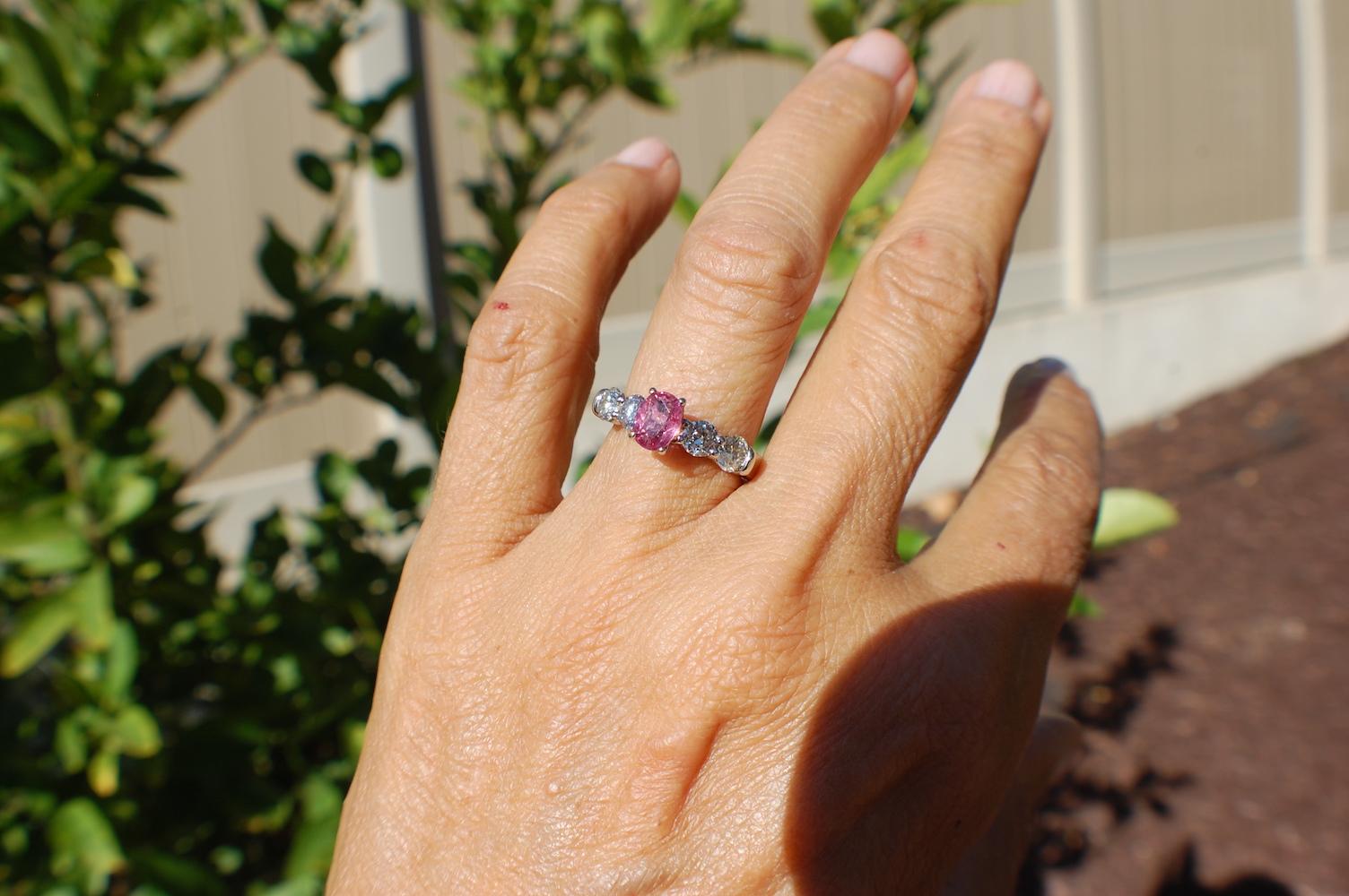 Pink Sapphire and Diamond 5-Stone Engagement Ring is set in  14 Karat white gold.  
 Pink Sapphire measures 6.77 x 5. 25 and is estimated at 1 carat. The quality is SI1 clarity and is a genuine pink sapphire. The color is a soft dusty pink that