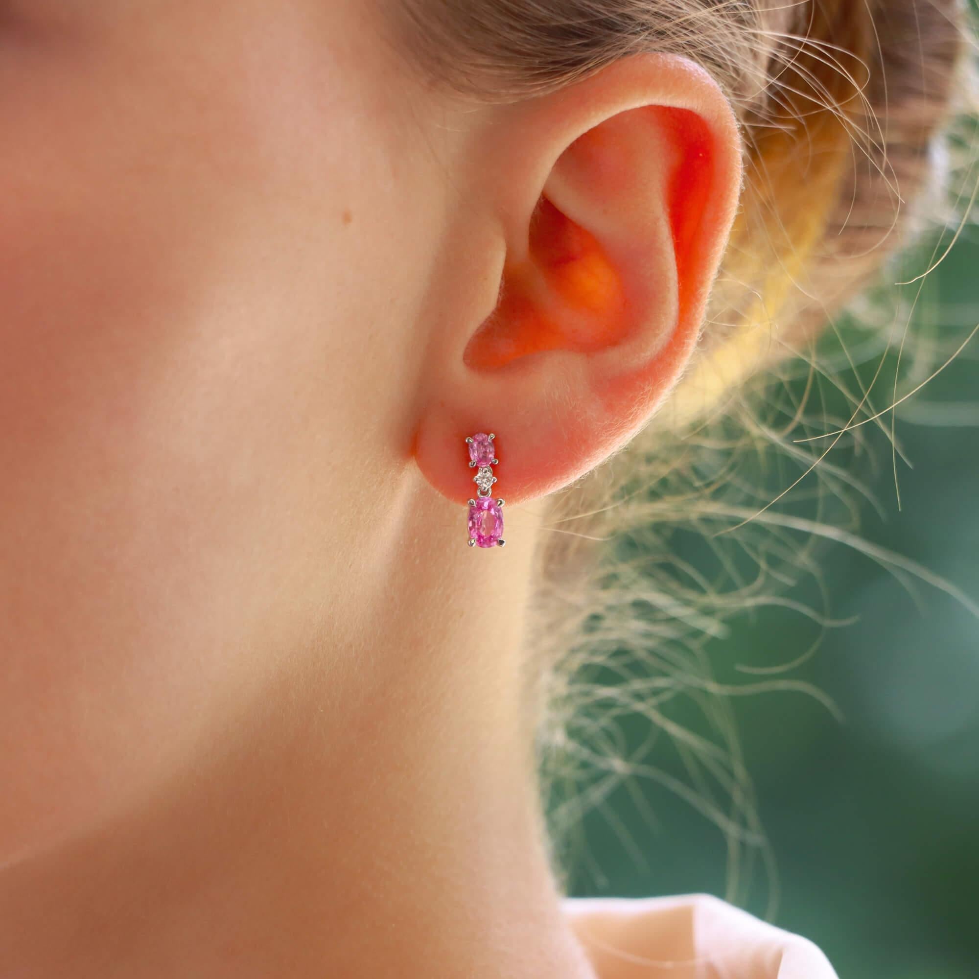 A beautiful pair of pink sapphire and diamond drop earrings set in 18k white gold.

Each earring is firstly composed of a small oval cut pink sapphire which is four claw set and secured to reverse with a post and butterfly fitting. Hanging from this
