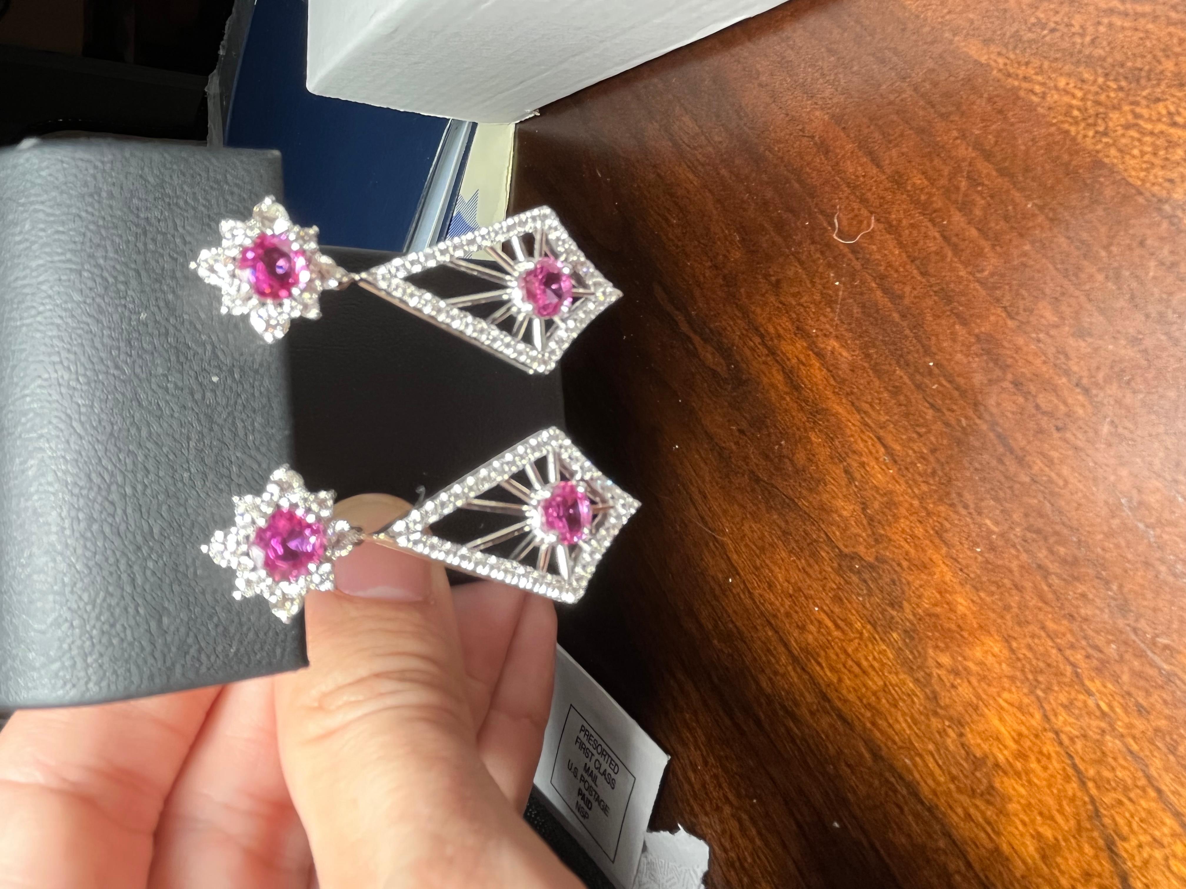 Einzigartig gestaltete Hängeohrringe mit rosa Saphiren von insgesamt 5,04 Karat in einem haloumrandeten Ohrstecker mit einem drachenförmigen Anhänger mit rosa Saphiren und weißen Diamanten und Goldakzenten. 