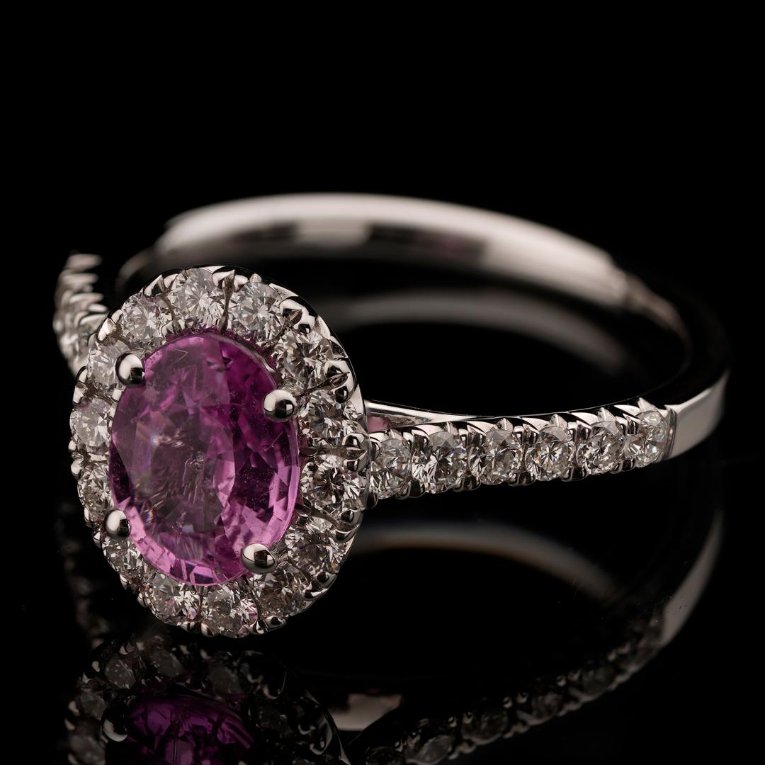 Fit for royalty, this 18 karat white gold ring boasts an eye-clean and completely untreated pink sapphire center stone with deep saturation of color, flanked in a single halo by 40 round cut white diamonds for a showpiece that sparkles from all