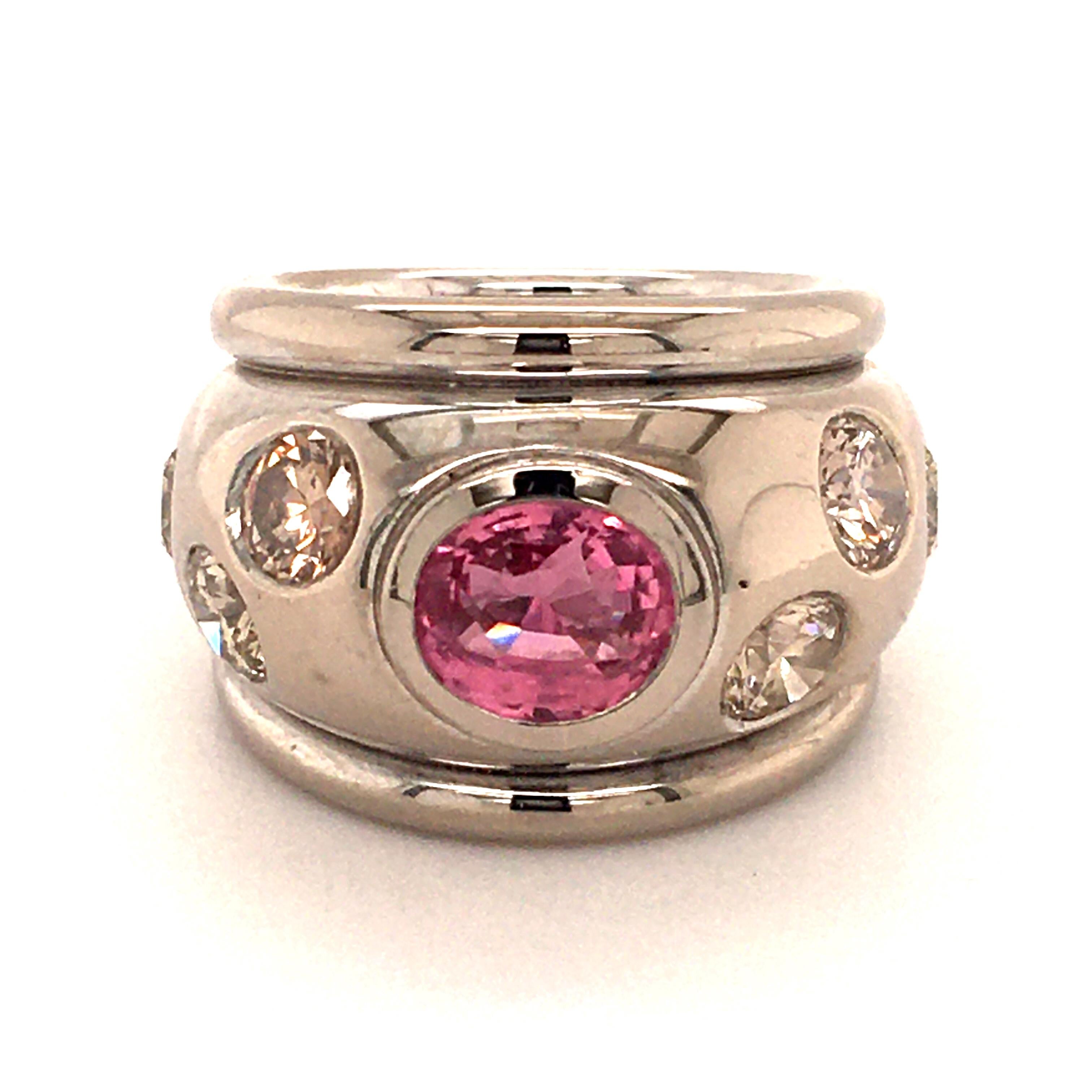 Questo audace e unico anello realizzato a mano in oro bianco 18 carati presenta uno zaffiro rosa non trattato di forma ovale di 2,58 carati e 6 diamanti taglio brillante di varie tonalità di marrone chiaro e purezza vs, per un peso totale di 2,50