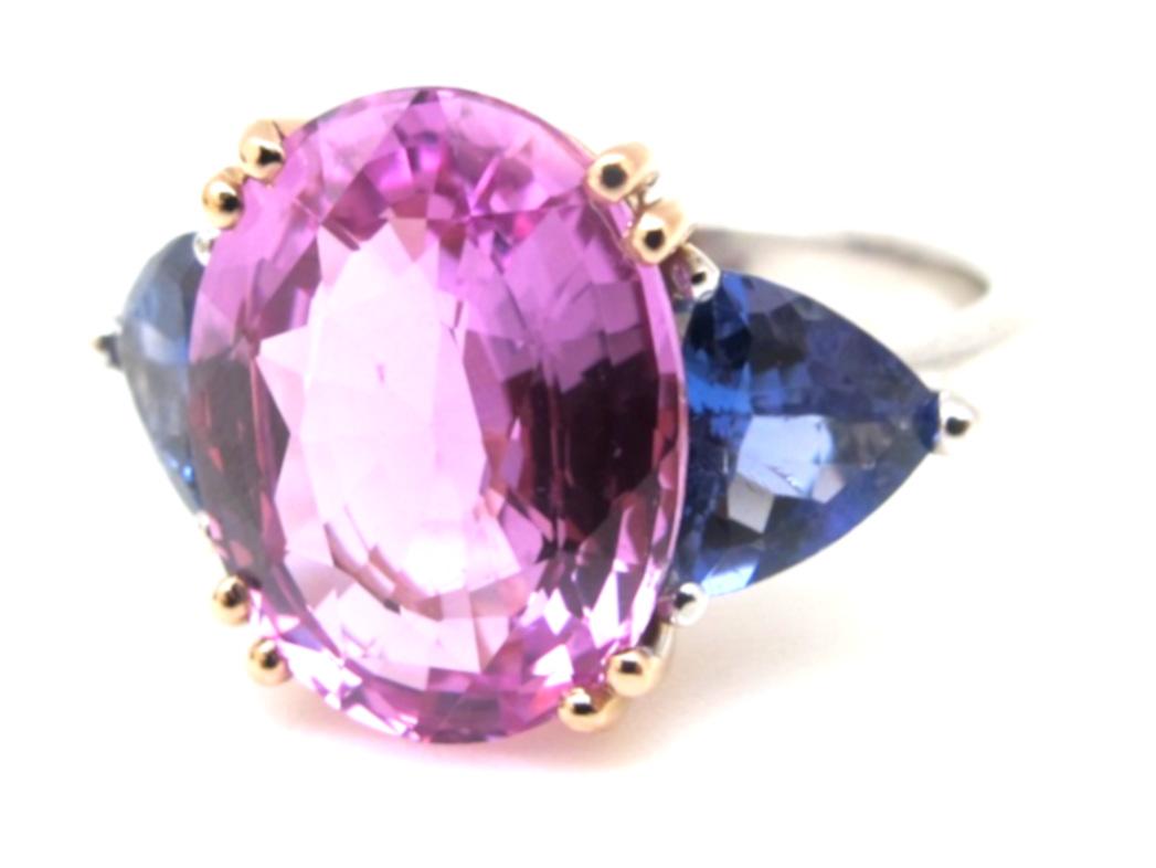 Pretty in pink... and violet! Not yo r typical 3-stone ring, yet could be used for a modern engagement. This beautiful Pink Sapphire (12.63x9.90mm/5.31cts) is eye-clean and comes with a GIA Certificate stating that it is heated. The stone is flanked