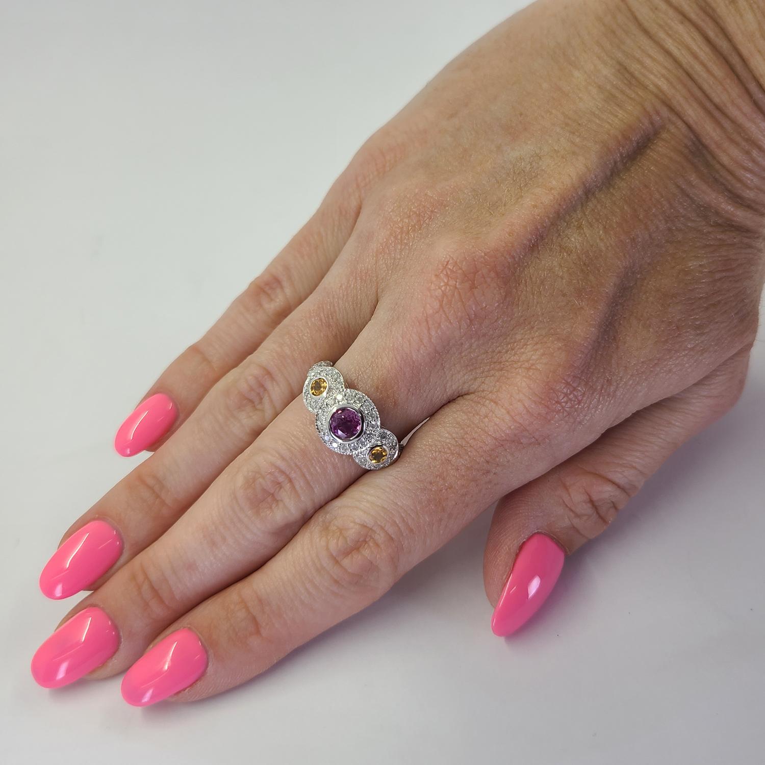 14 Karat White Gold Three Stone Ring Featuring A 0.40 Carat Round Bezel Set Pink Sapphire and Two Bezel Set Round Citrines Totaling 0.20 Carats Accented By 68 Round Brilliant Cut Diamonds of I Clarity and H/I Color Totaling An Additional 0.34