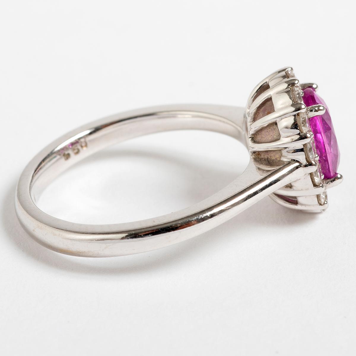 Our very pretty cluster ring features a large pink sapphire of est .5ct and is surrounded by fourteen diamonds est combined .5ct of 1st. SI2, set in and on a 18k white gold band. The ring size is 6.25 (US) M (UK). A perfect statement piece.
