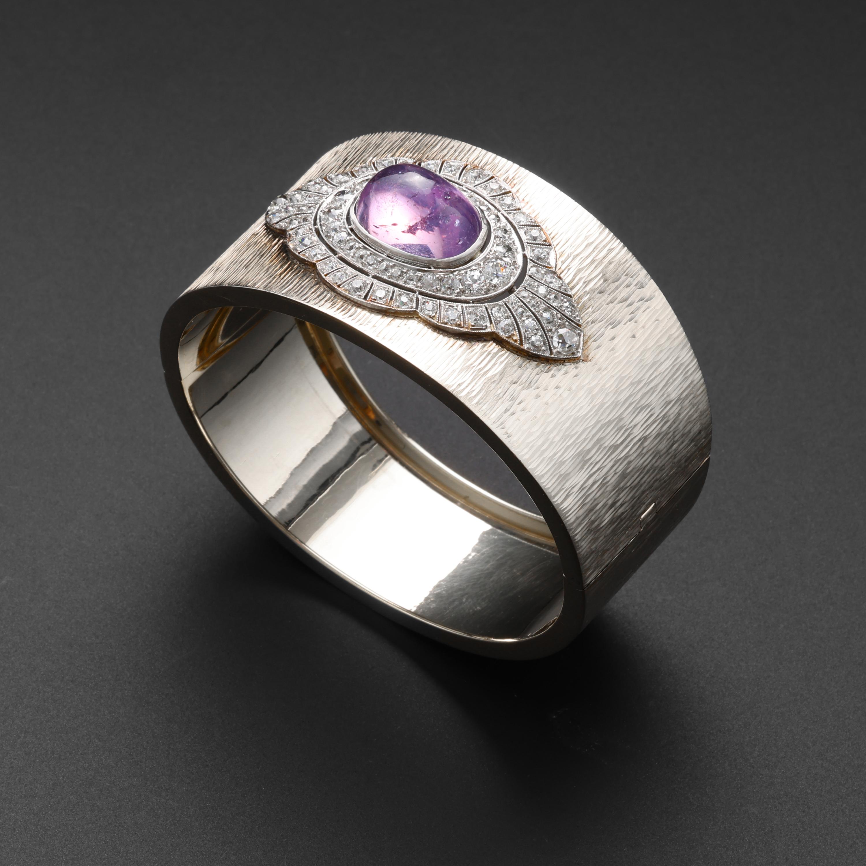 This glamorous and one-of-a-kind cuff bracelet was created by American jeweler, Marcus & Co in the 1940s. The 14K white gold cuff bracelet features an oval cabochon-cut pink-purple natural star sapphire that measures 15.66mm x 10.8mm x 8.19mm and