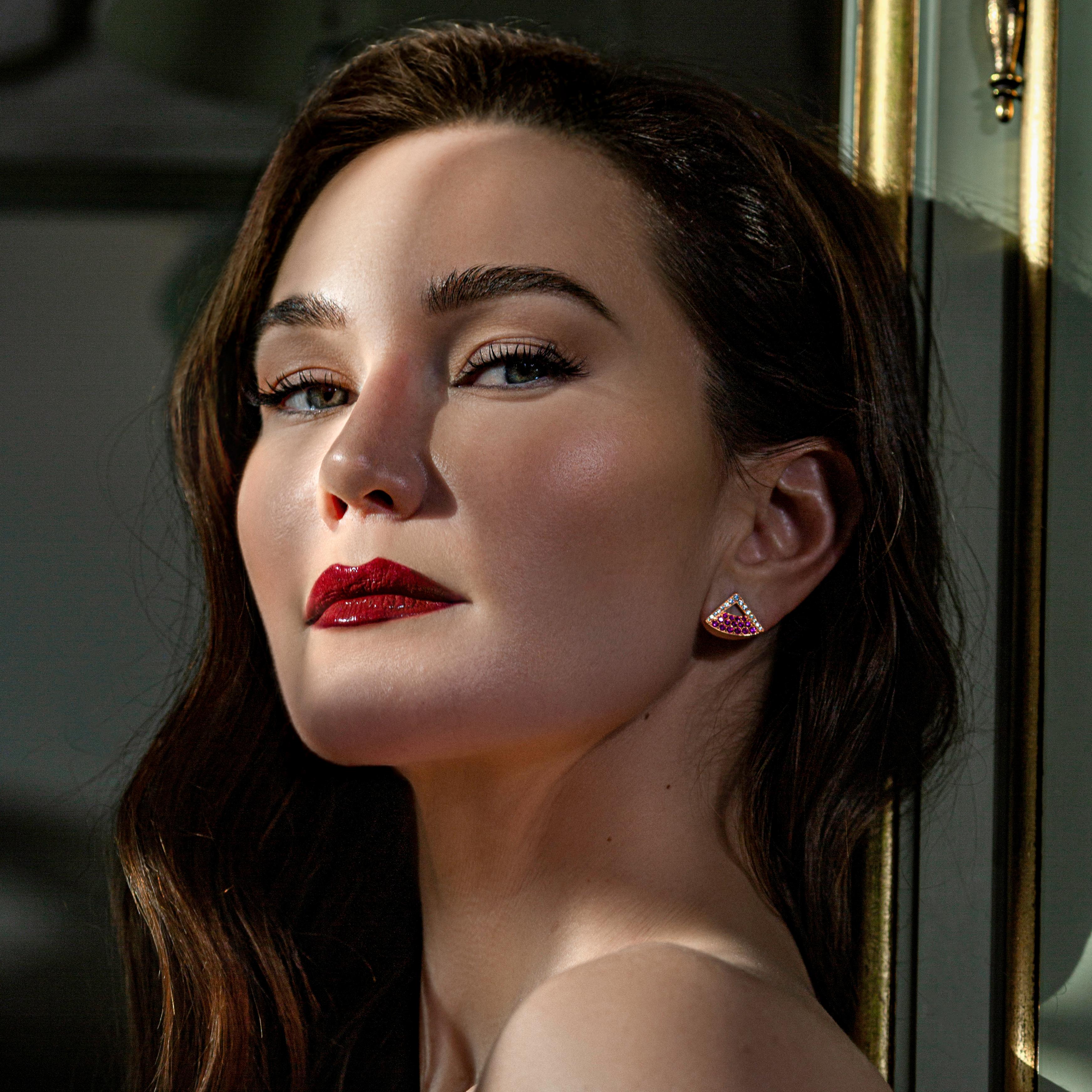 Pink sapphires totaling 0.65 carats and graduating diamonds totaling 0.30 carats complement each other in these earrings which feature a cut-out negative space following the curve of the ear lobe. 

The designer wanted to create earrings that seemed