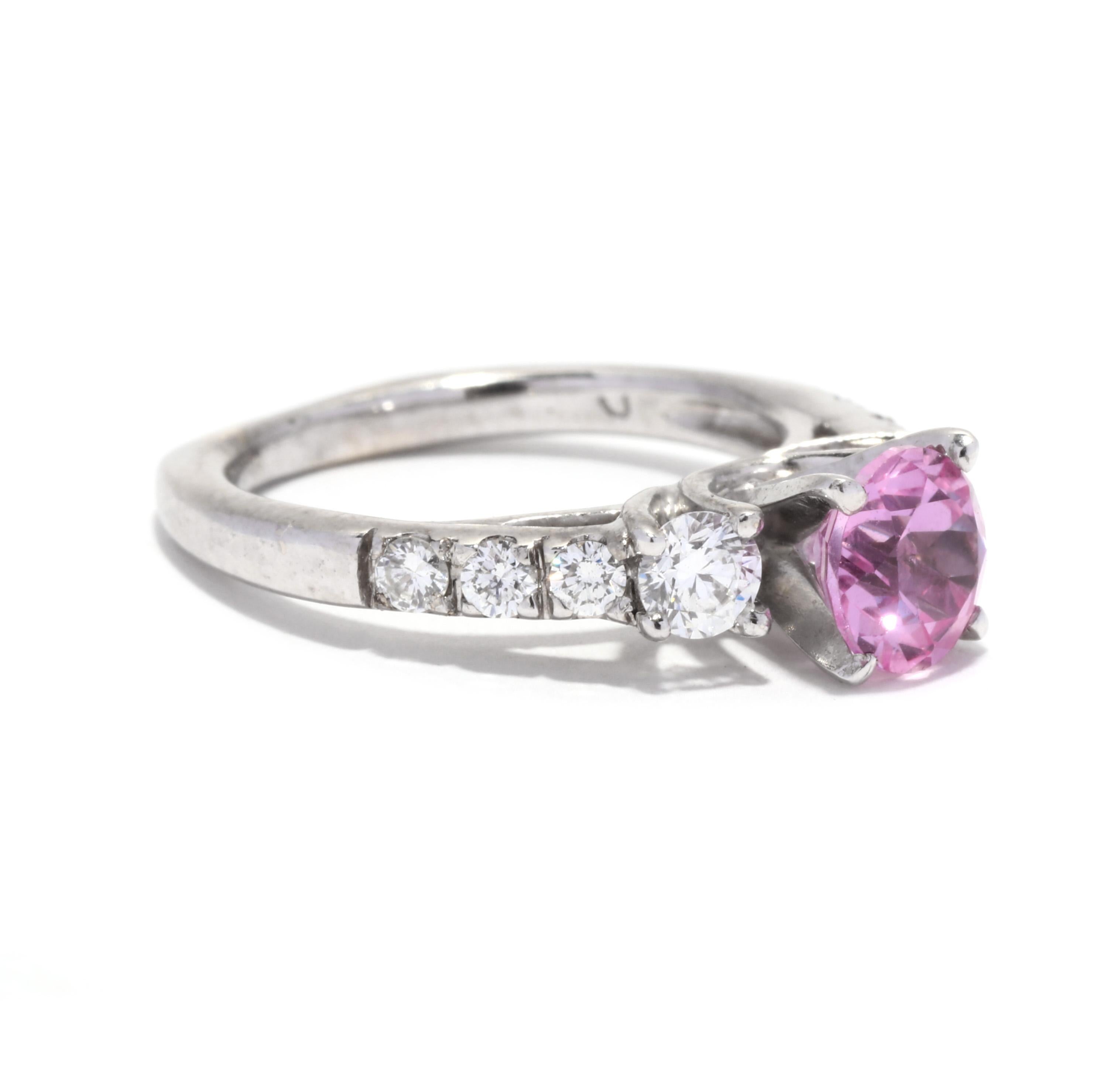 An 18 karat white gold created pink sapphire and diamond engagement ring. This statement ring features a prong set, round brilliant cut created pink sapphire weighing approximately 1.15 carats with diamonds down the band weighing approximately .60