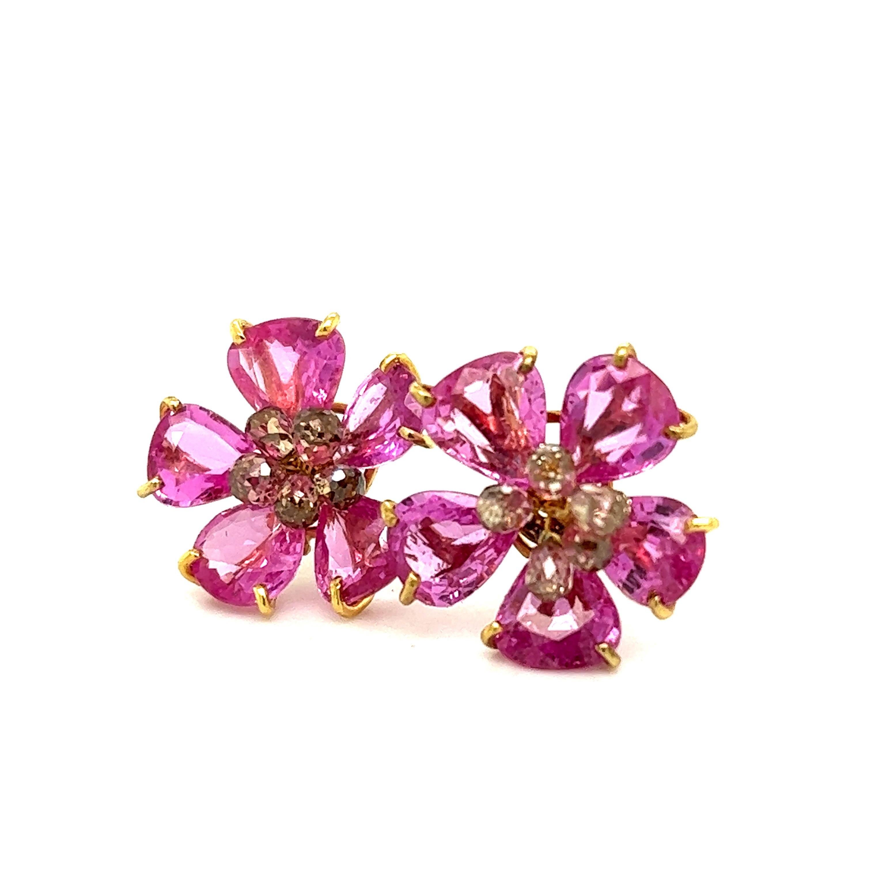 One hand crafted pair of earrings made in 18k yellow gold. The pair are floral themed and set with natural pink sapphire gemstones and champagne colored diamonds.
The earrings are set with ten pear shaped pink sapphire gemstones that display a