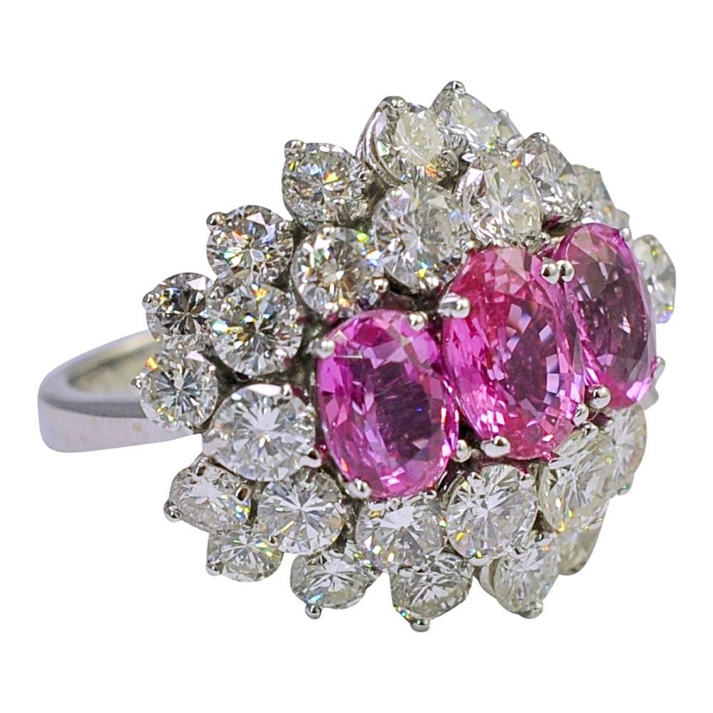 Spectacular pink sapphire, diamond and 14ct gold ring; this dramatic ring is set with 3 pink, oval, mixed cut sapphires weighing 2.70ct;  there are two rows of sparkling brilliant cut diamonds encircling the sapphires with a total diamond weight of