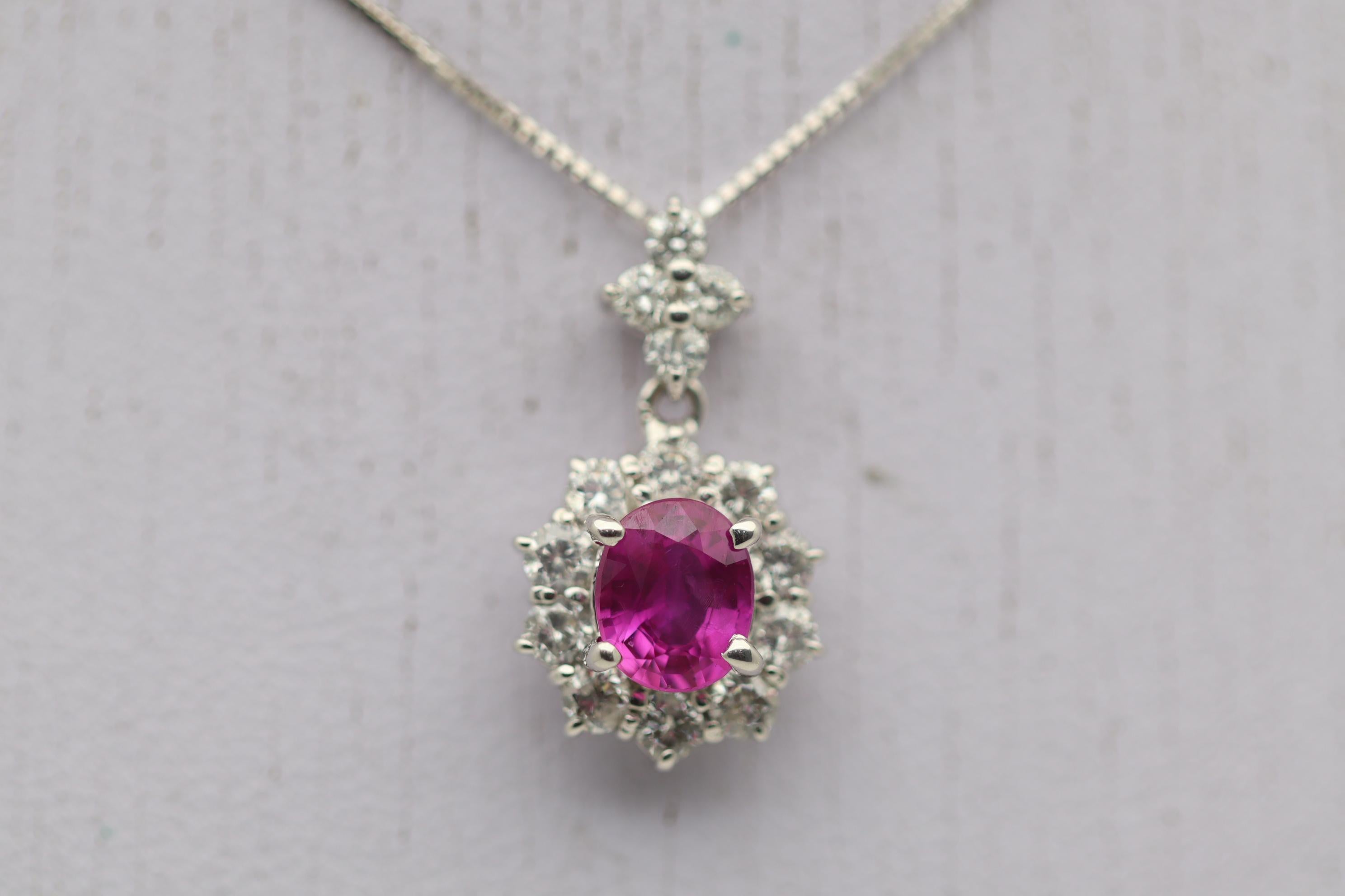 A lovely intense reddish-pink sapphire takes center stage! The color is so strong and vivid that some will consider this stone as a ruby. It weighs 1.09 carats and is oval shaped. Surrounding the sapphire is a halo of round brilliant-cut diamonds as
