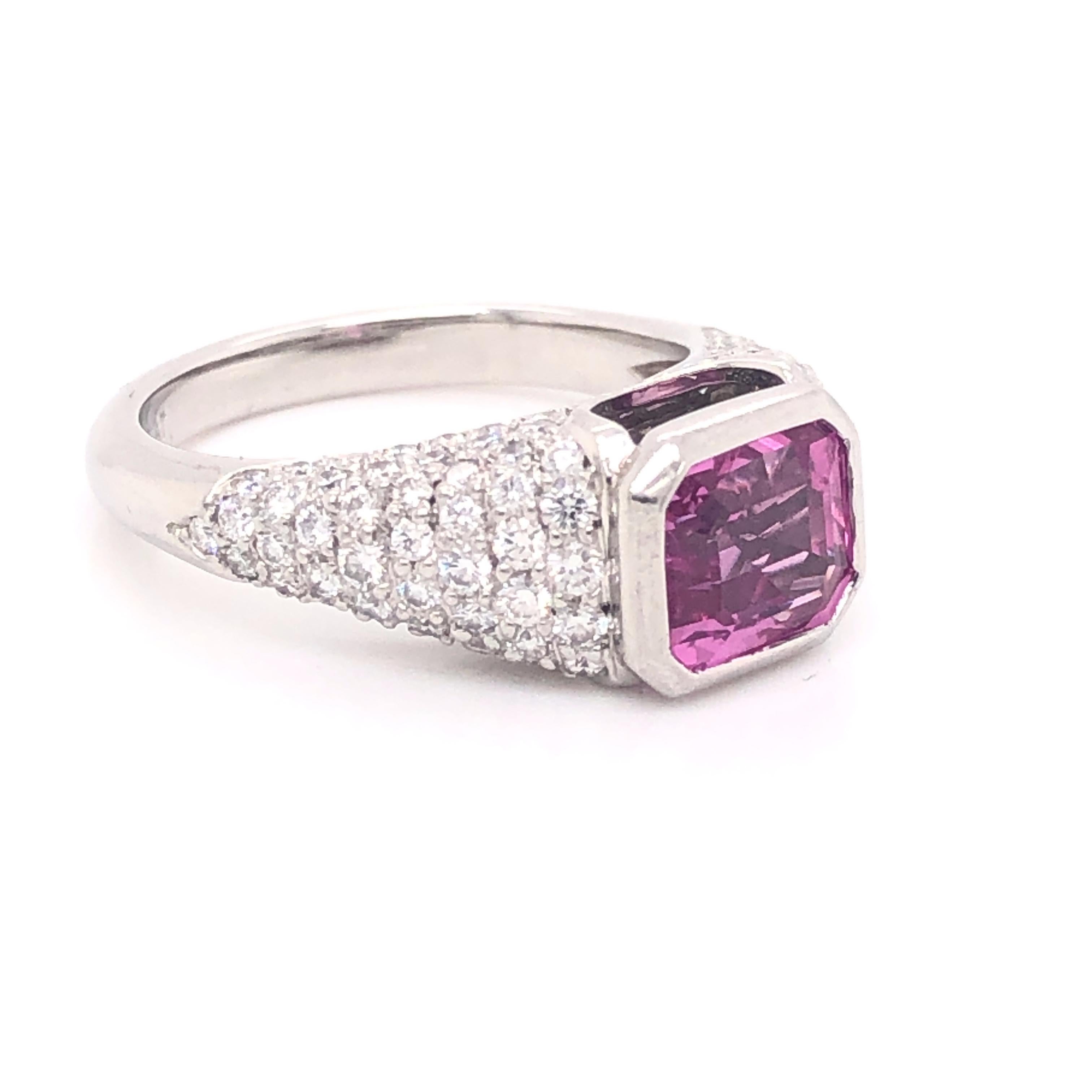 Beautiful ring crafted in platinum. This elegant design showcases a Pink Sapphire with a rich deep color. The design of the ring truly flows as this ring was custom made for this beautiful gemstone. The pink sapphire is a emerald cut gemstone set in