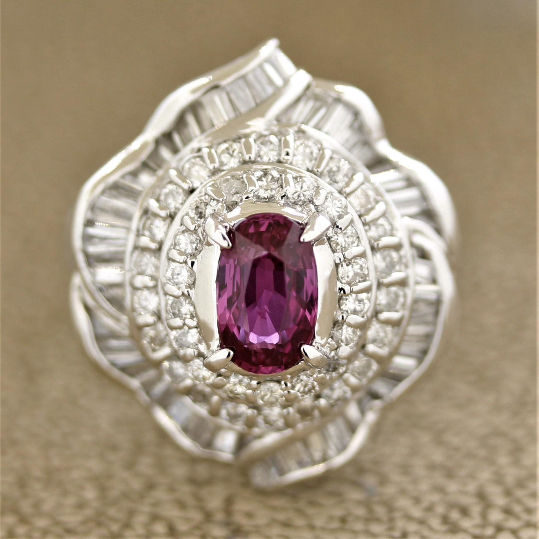A platinum ring featuring a superb gem quality pink sapphire. It has a bright and vivid reddish-pink color almost making the stone a ruby! It weighs 1.06 carats and is cut as a long oval shape and is free of any visible inclusions. It is accented by