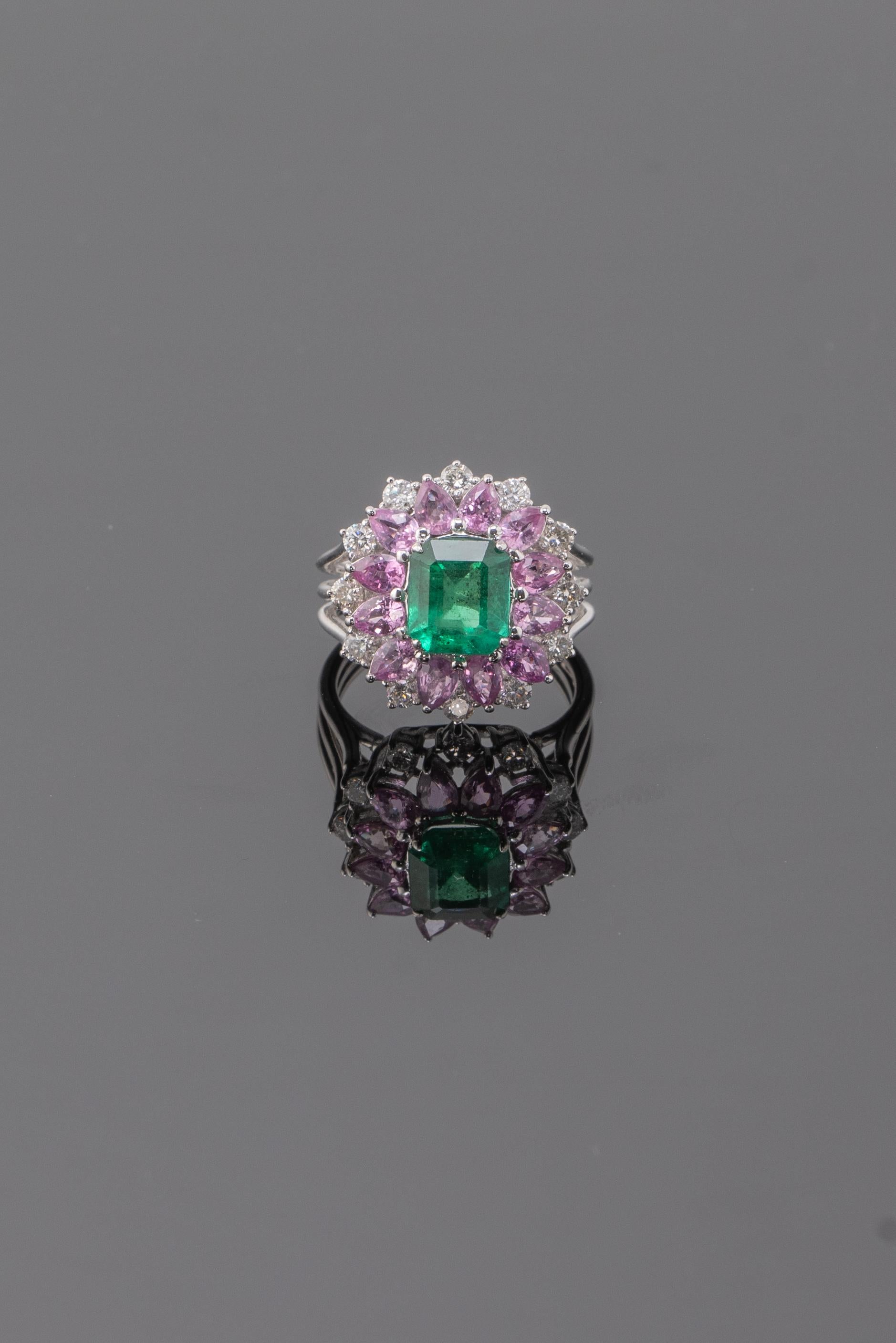This ring features a stunning rich green 3 carat Emerald, surrounded with lovely 2.82 carats Pink Sapphire and 0.69 carats Diamonds that makes it eye-catching, all set in 7.83 grams of solid 18K White Gold. Currently sized at US 6, can be