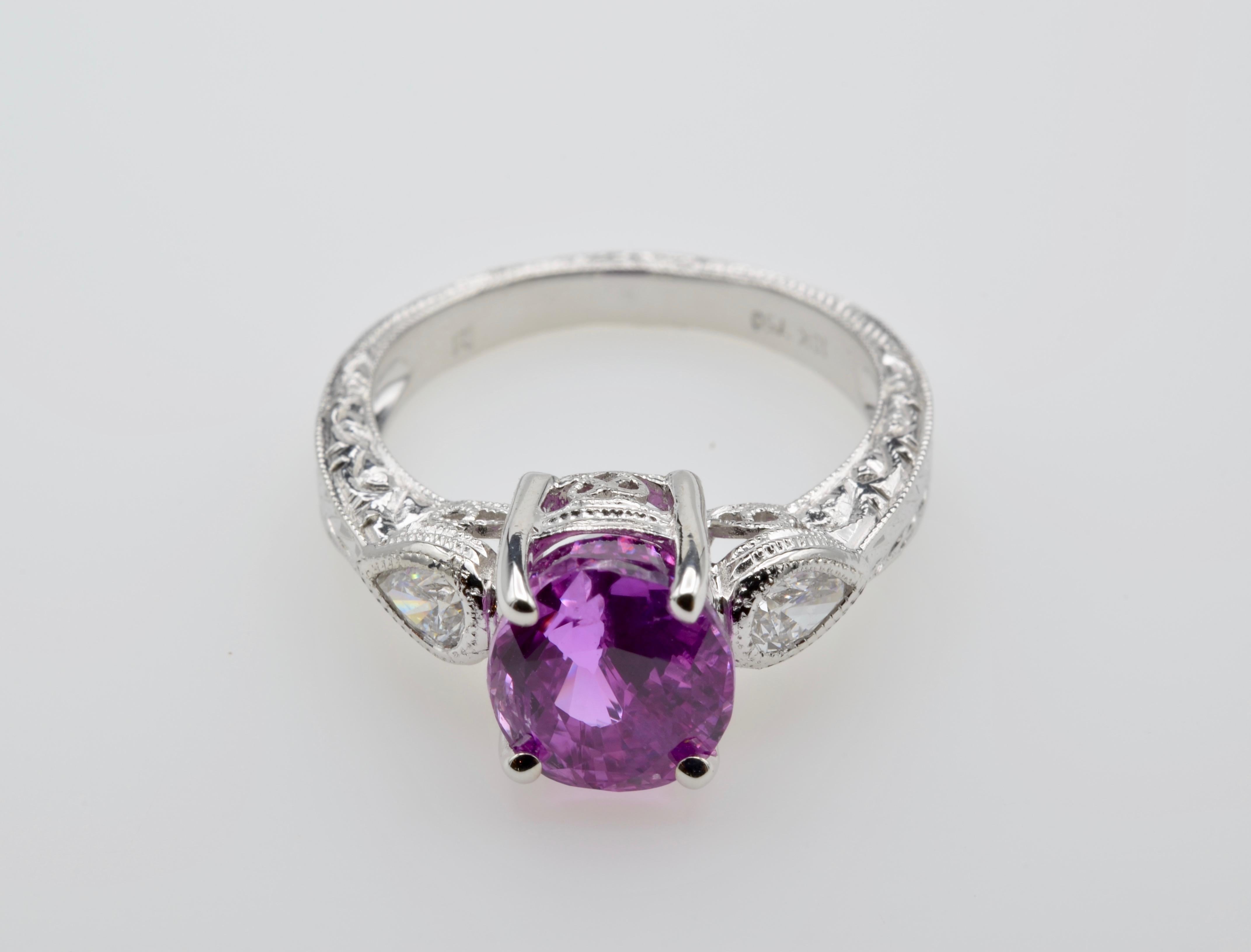 3.74 carats of brilliant Pink Sapphire set in a white gold prong setting. This stunner has two pear shaped diamonds, one on each side, and is set in the most intricate of designs. A tapered band of braided feather-like detail wraps around a size 7.