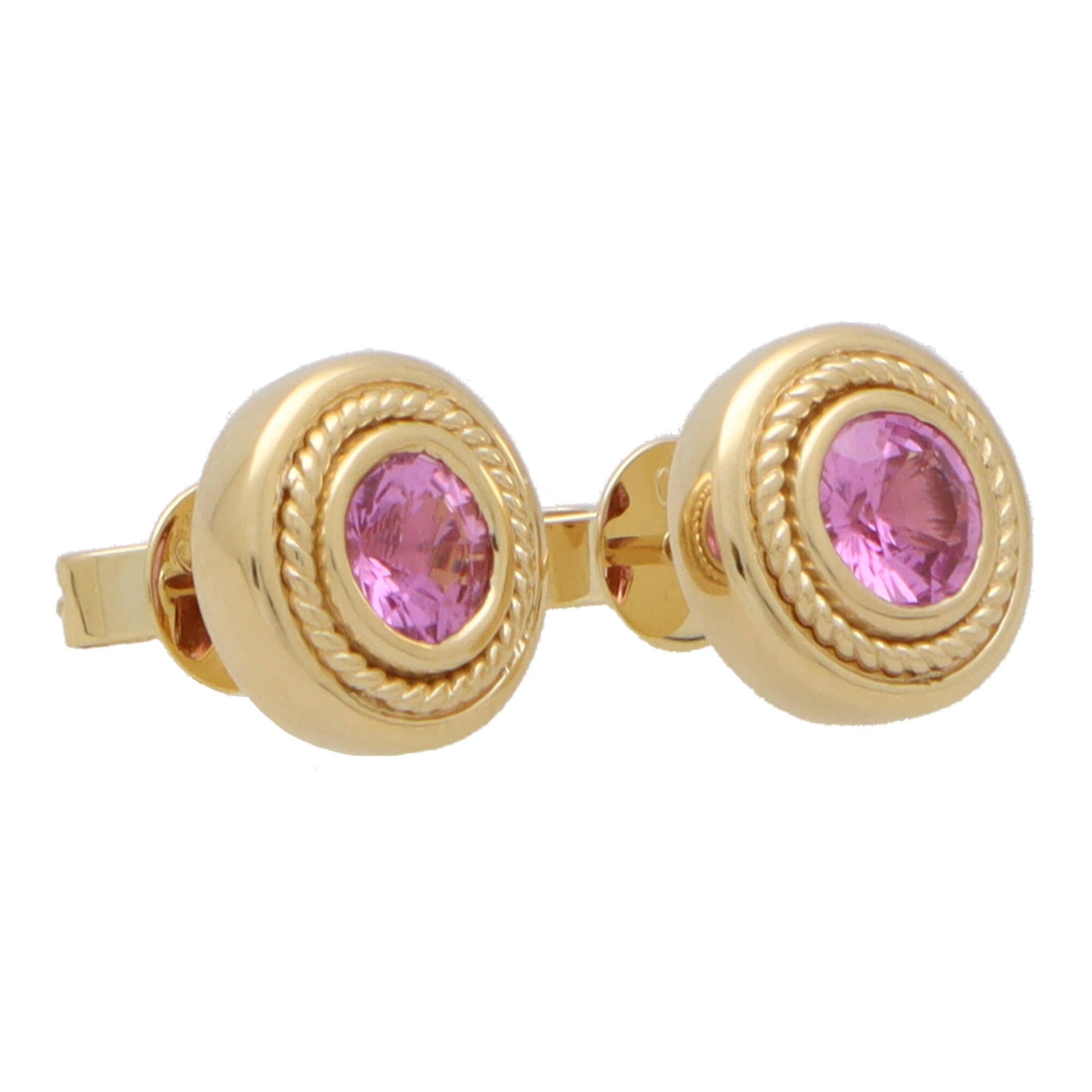 An incredibly stylish pair of Etruscan inspired pink sapphire stud earrings set in 18k yellow gold.

Each earring is solely set with a 0.58 carat round cut pink sapphire which is securely set in a chunky yellow gold rub over setting. The edging