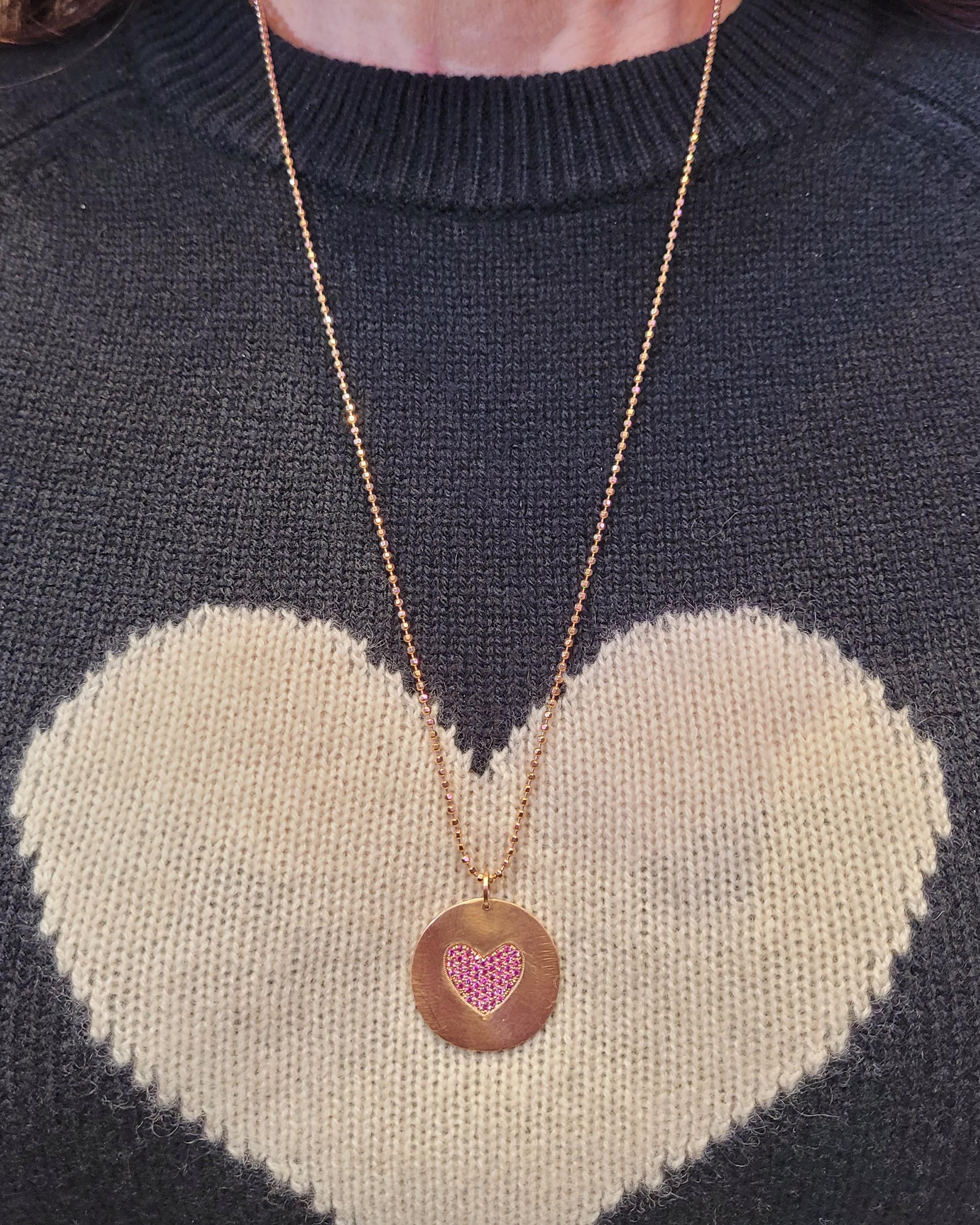Ce ravissant collier à chaîne avec pendentif en forme de cœur en saphir rose est une incarnation de l'amour et de l'élégance. Le collier comporte un pendentif rond au cœur duquel de délicats saphirs roses forment de manière complexe un symbole