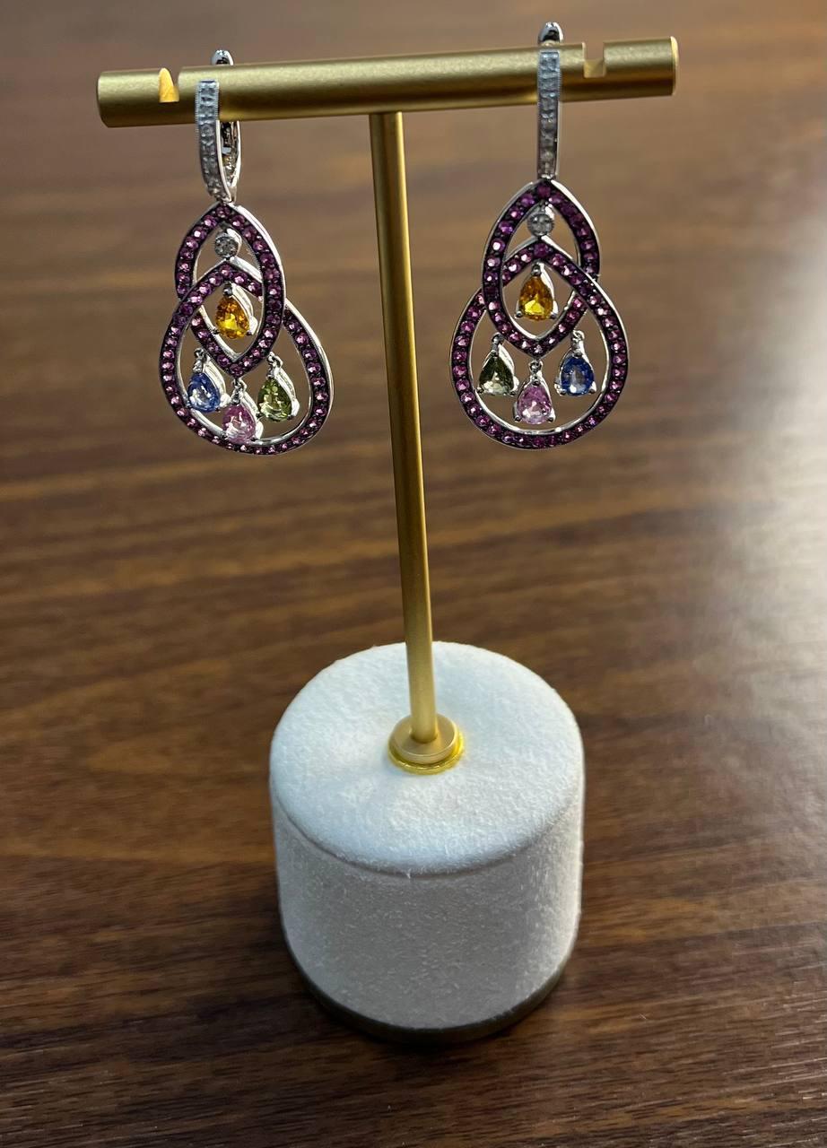 These exquisite earrings feature a captivating design with pear-cut gem stones in a variety of colors. The intricate arrangement includes a series of interlocking loops adorned with vibrant gemstones, creating a stunning visual effect. The earrings