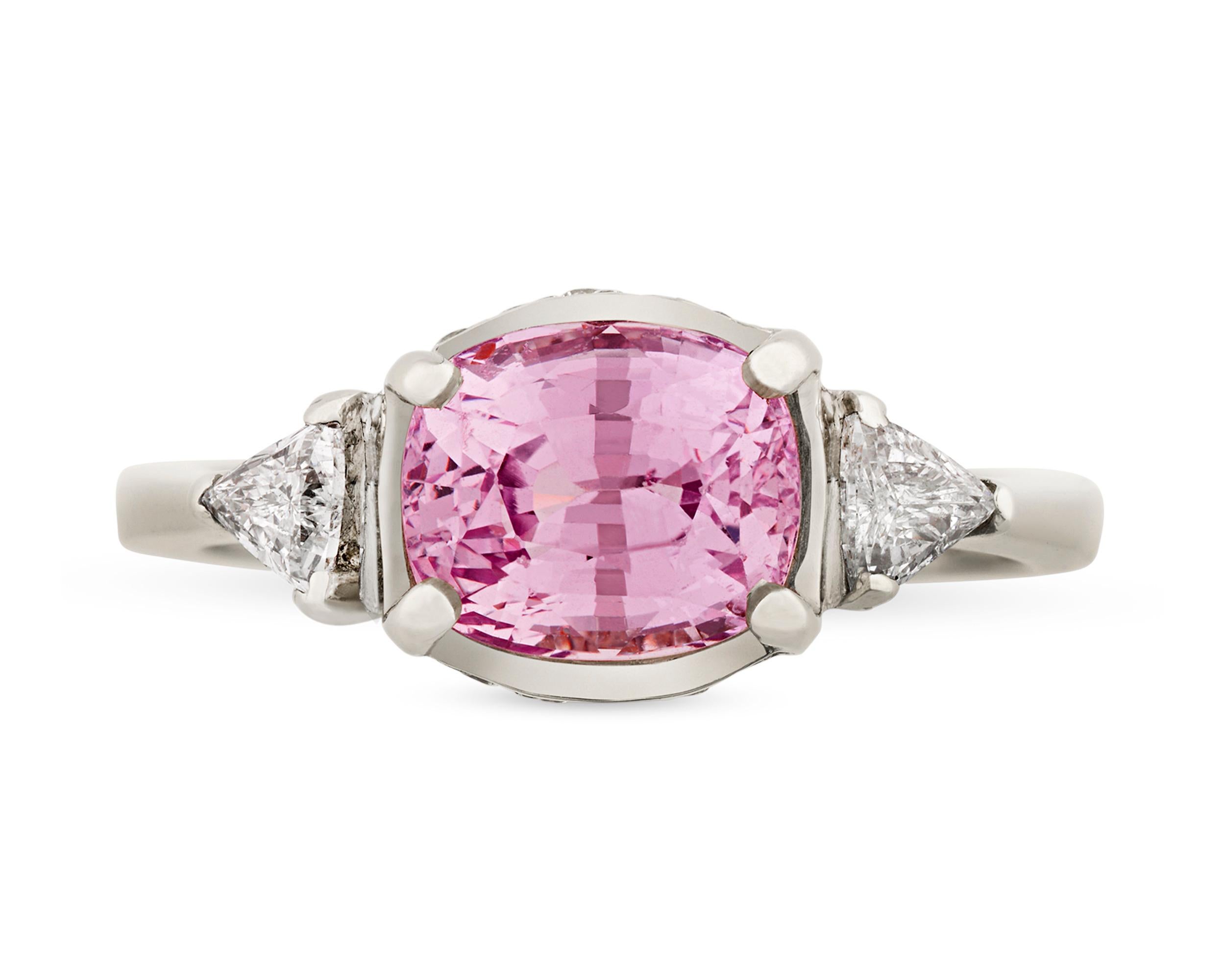 A rare cushion-cut pink sapphire is the star of this ring. Pink is among the most coveted hues in which to find this colorful gem, and the distinctive, rosy tone of this 3.21-carat stone is truly remarkable. Accented by 0.70 total carat of white
