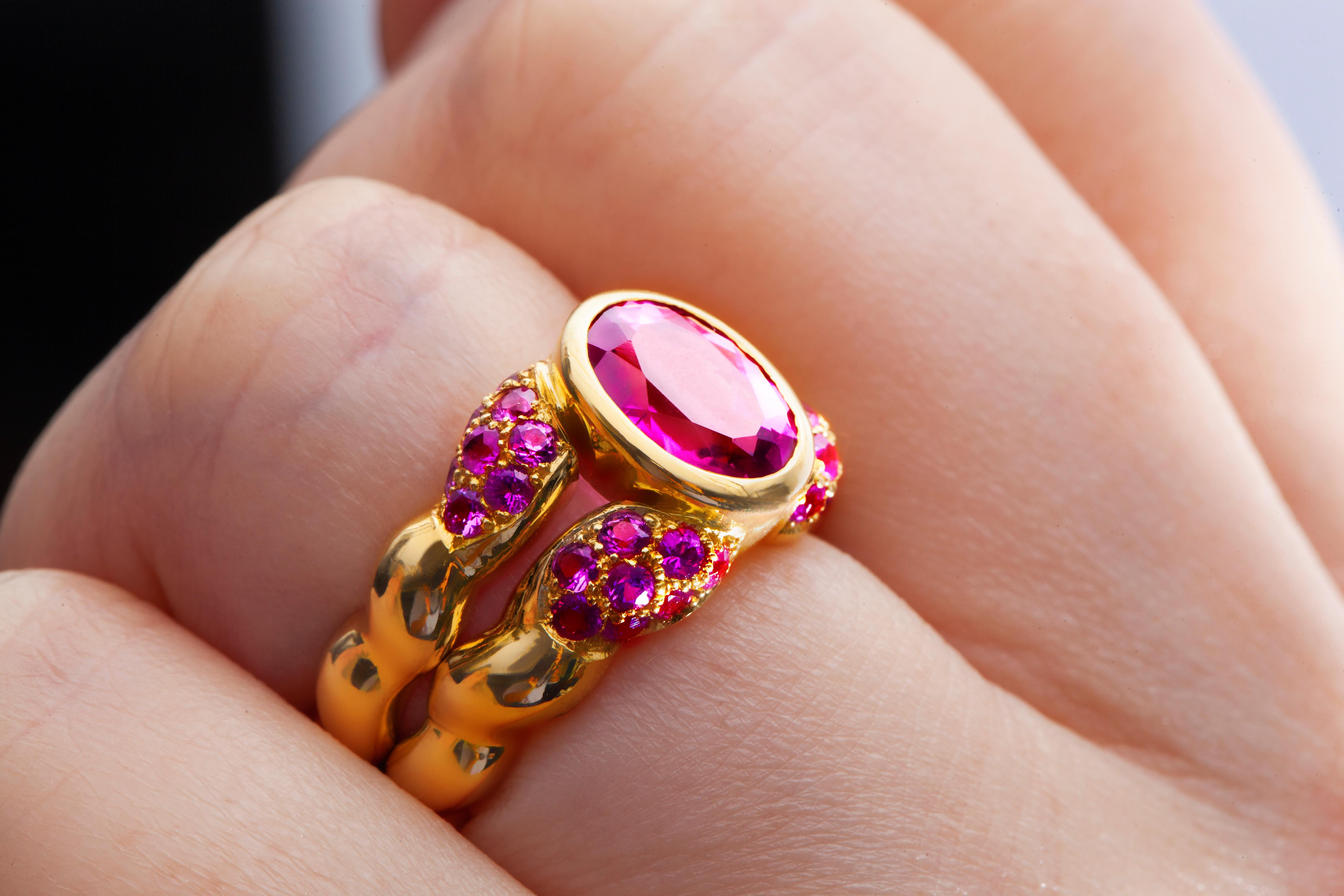 Pink sapphire ring with an center oval pink sapphire weighing 1.76cts surrounded by 32 round pink sapphires weighing 1.02cts total and handmade in 18k yellow gold.